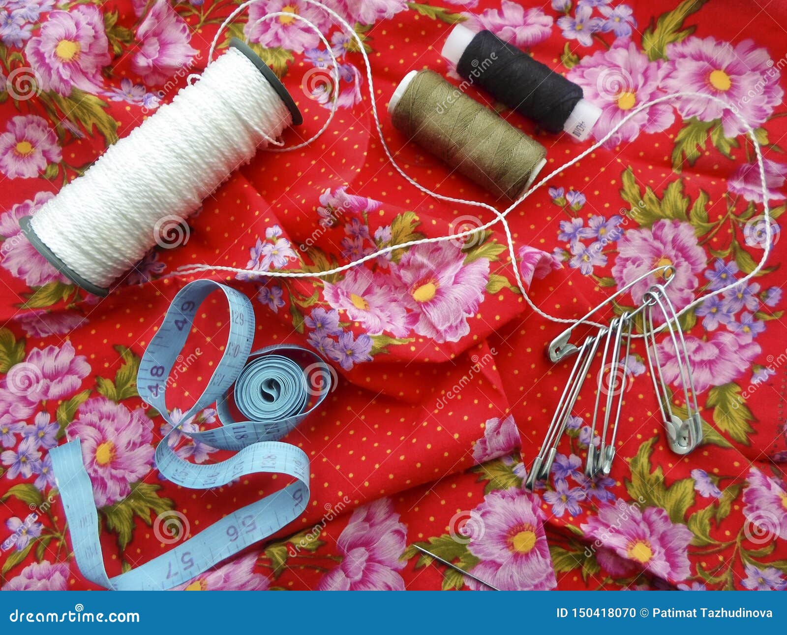 Sewing Tools Colored Sewing Threads, Centimeter Ribbons and Colored Pins on a Red Background
