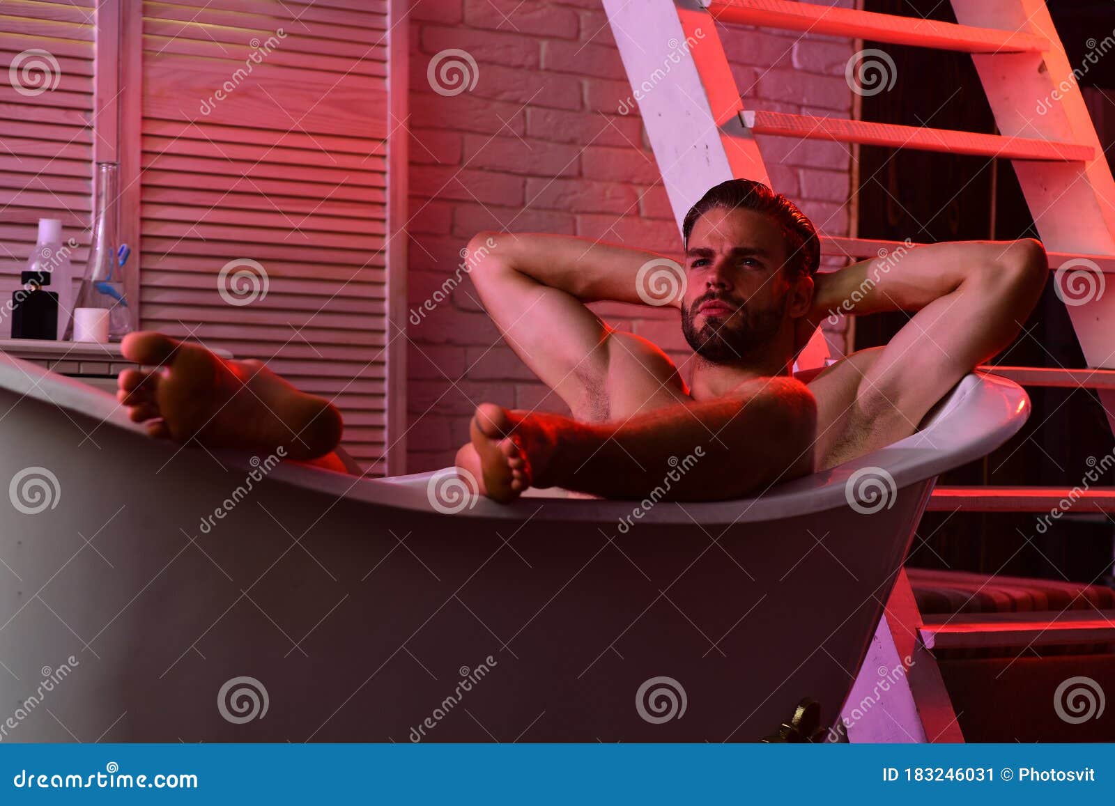 erotica concept: macho sitting in bathtub with red lights on