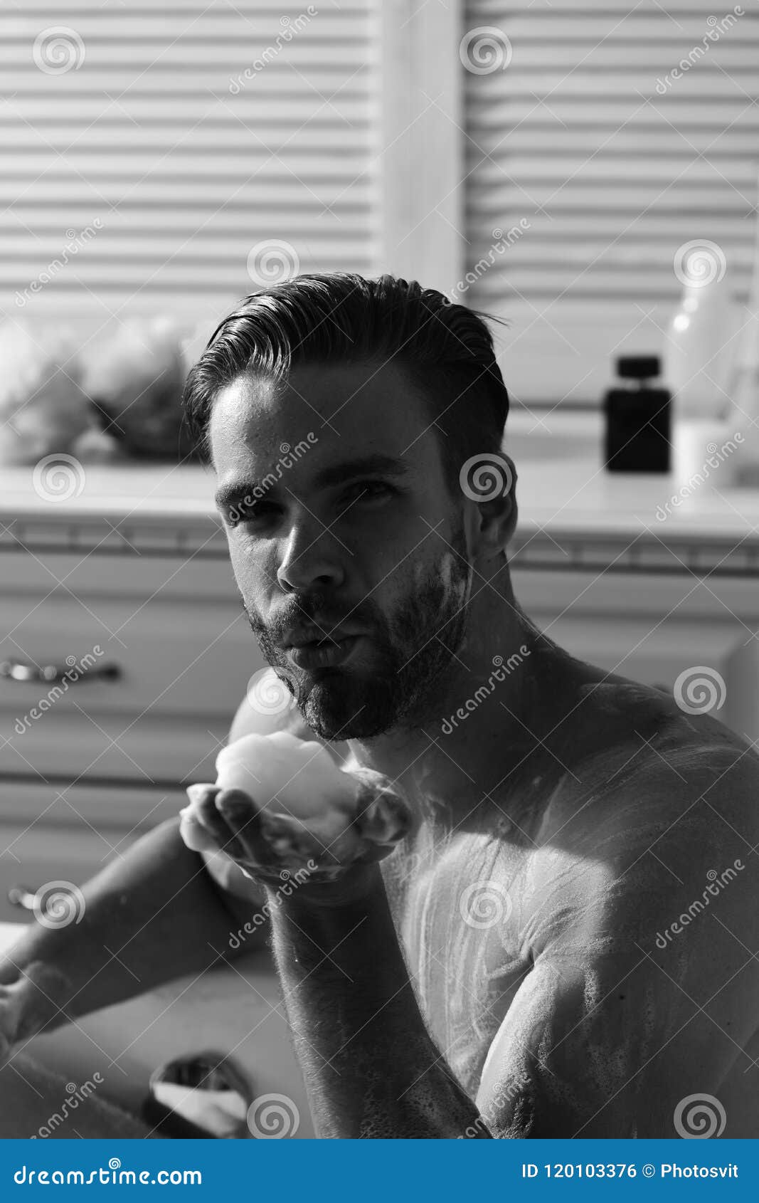 sex and erotica concept. man with beard and seductive face blowing foam from palm. man with beard and seductive face