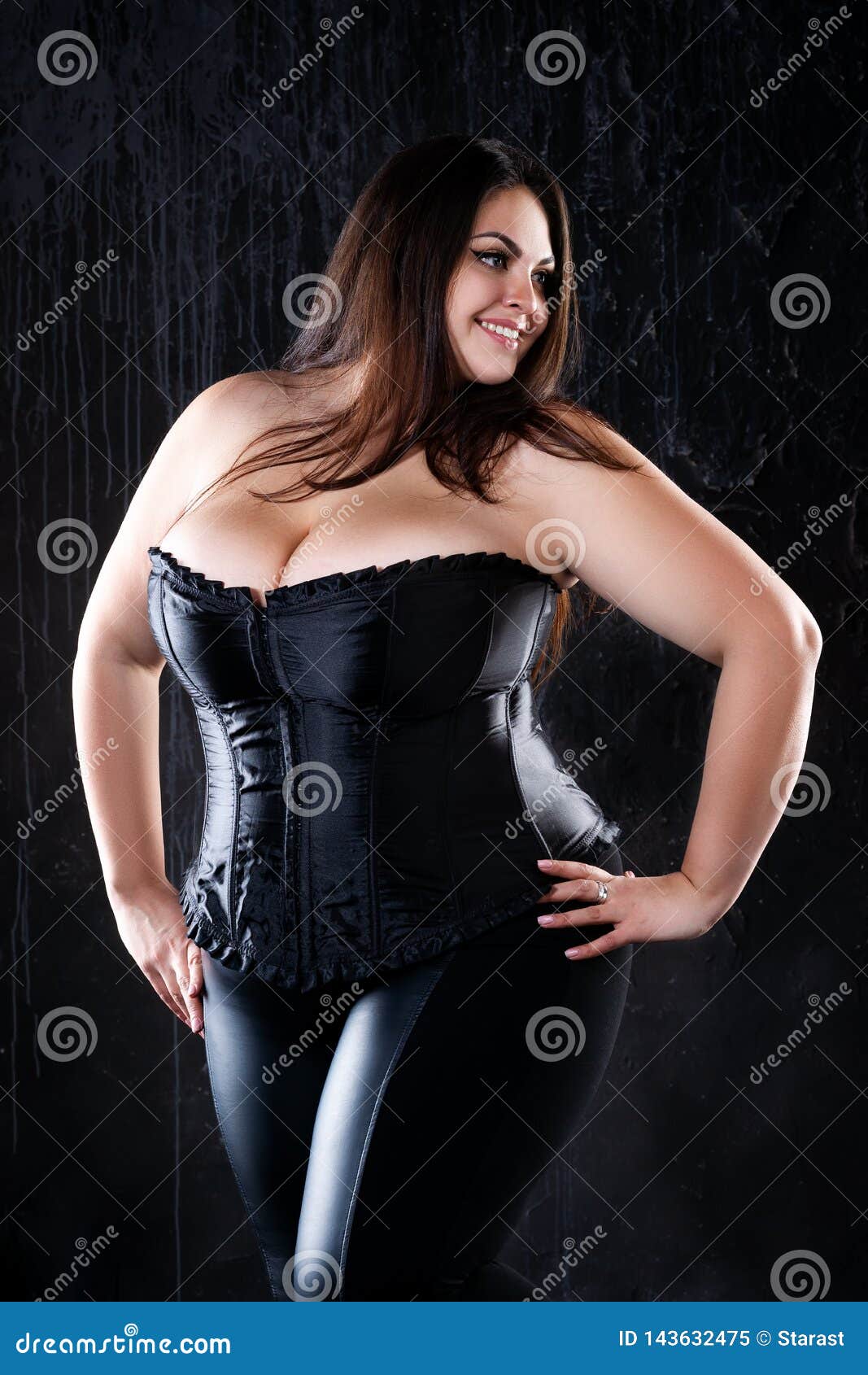 Sexigt plus formatmodell i den svarta korsetten, fet kvinna med stora naturliga bröst på mörk bakgrund, positivt begrepp för krop