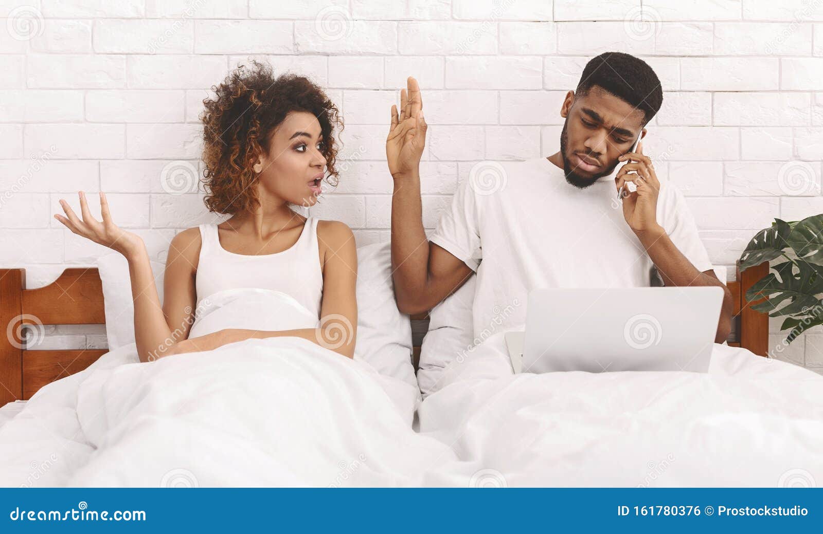 african workaholic husband ingnoring his iiritated wife in bed