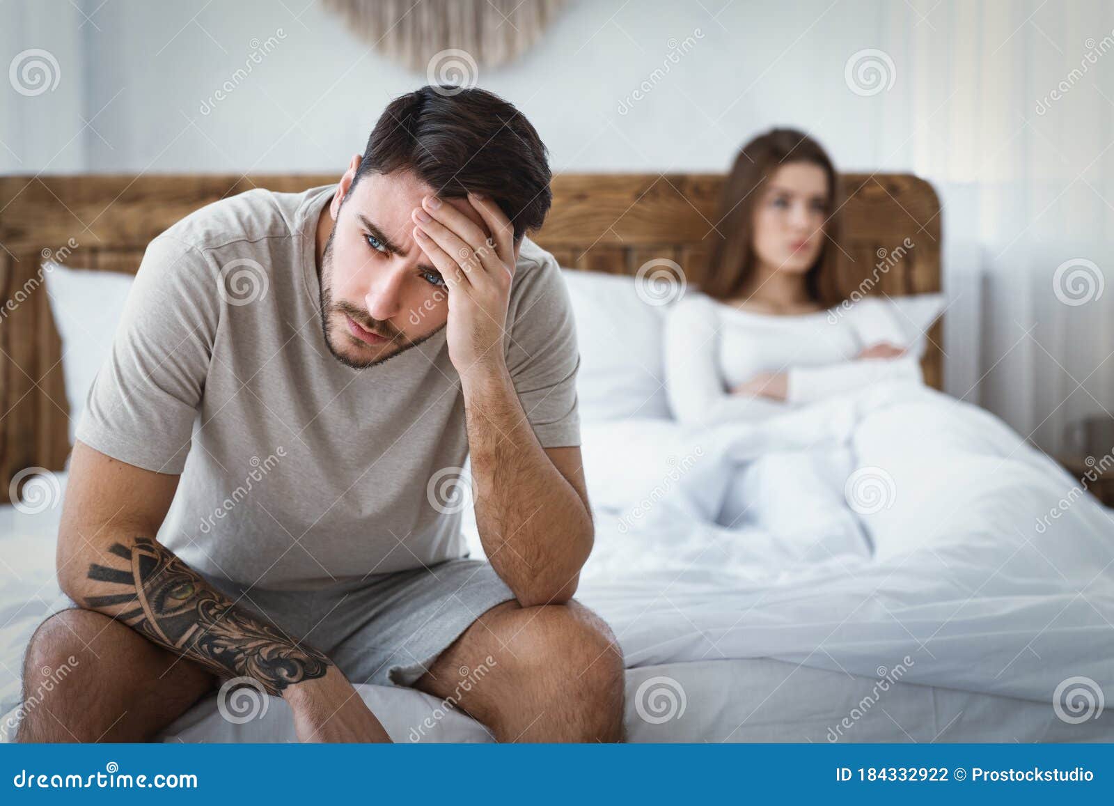 sexual dysfunction. husband holds his head, upset wife on bed