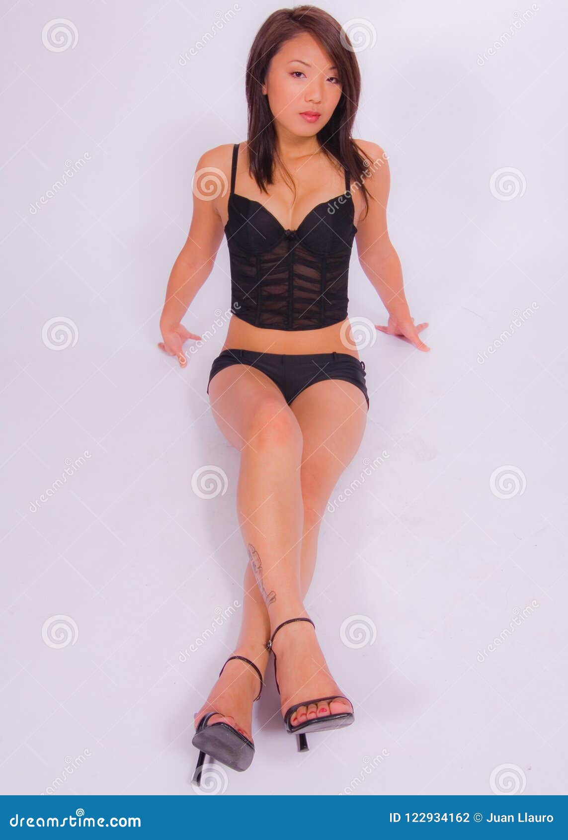 Asian Woman Wearing Black Lingerie and Black High Heels Posing Against a White Background Stock Photo pic