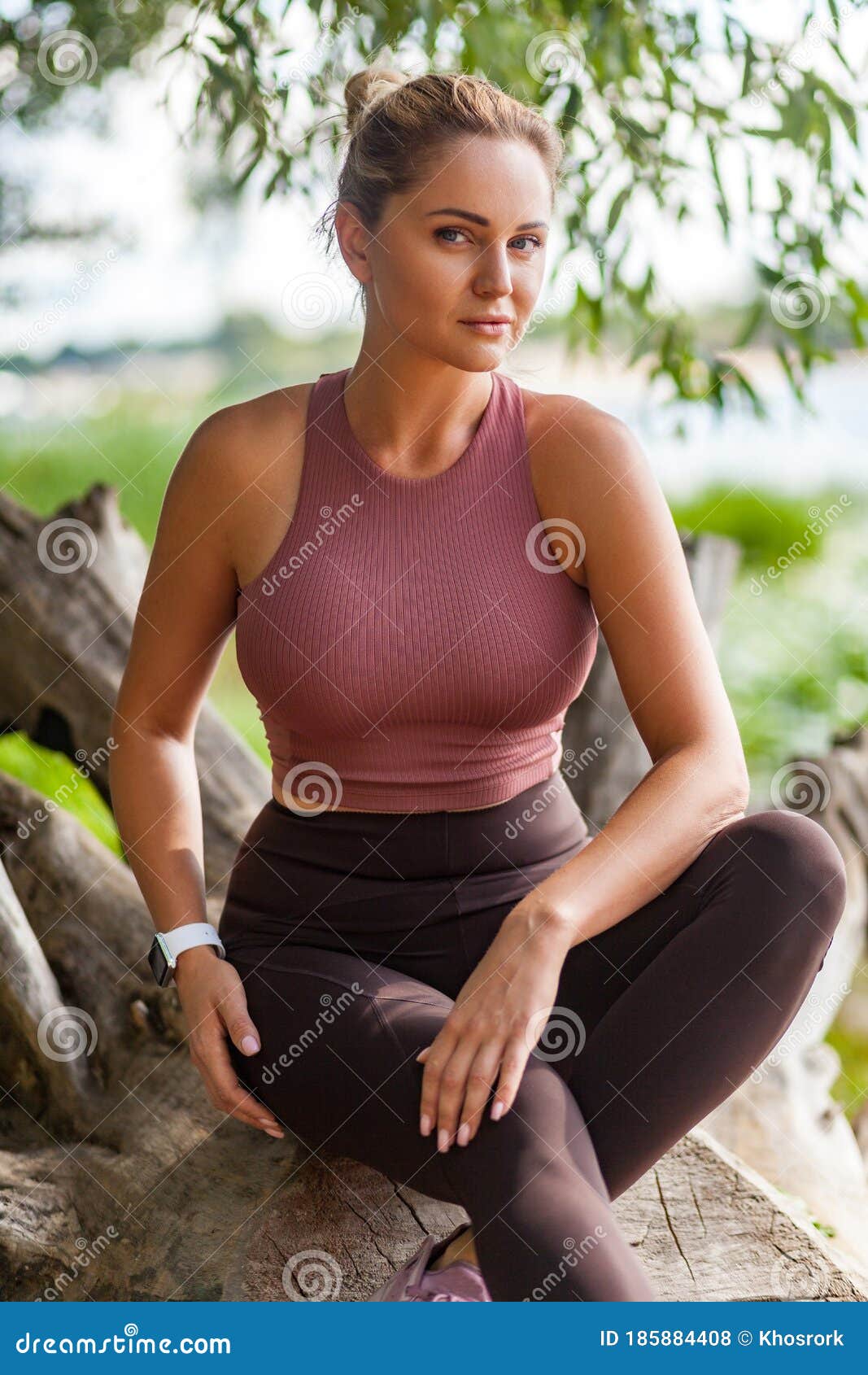 Attractive Woman in Yoga Pants and Top Sitting in Forest Taking