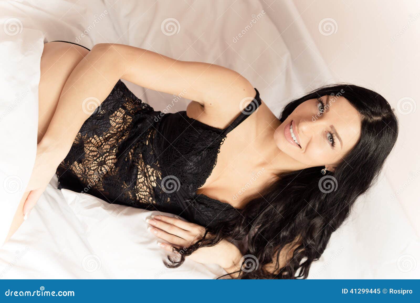 Brunette Girl with Blue Eyes in Black Lingerie Lying on White Bed Looking at Camera Smiling Portrait Image Stock Image photo
