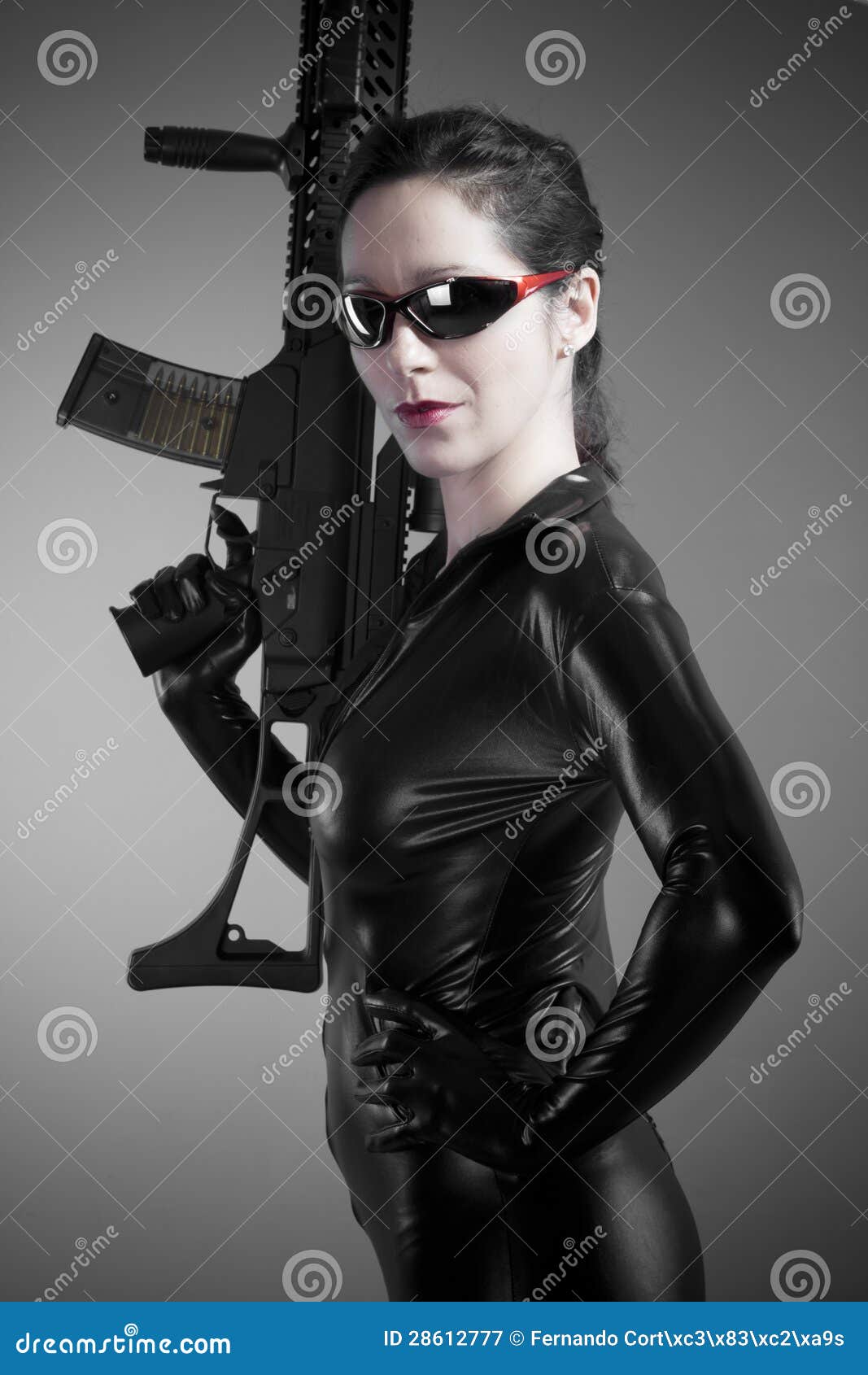 Brunette Woman In Latex Jumpsuit With Heavy Gun And