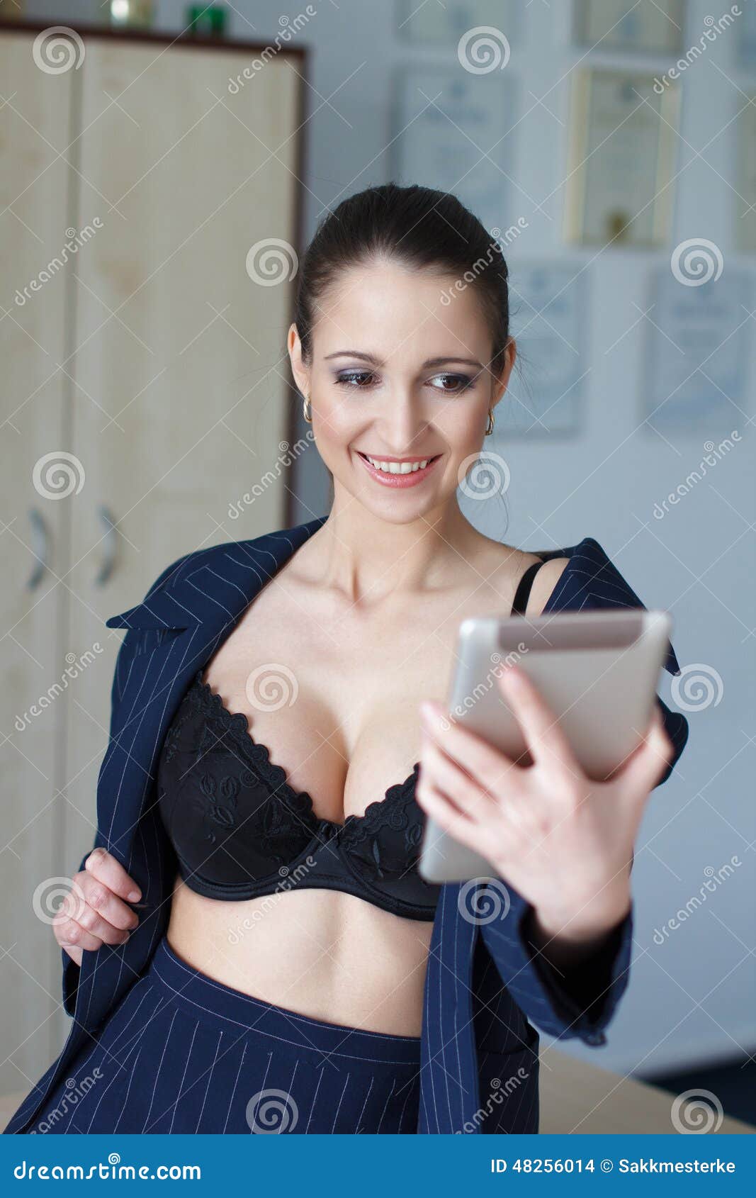 Looking down on female woman in only bra with ample breasts cleavage using  laptop computer at night фотография Stock
