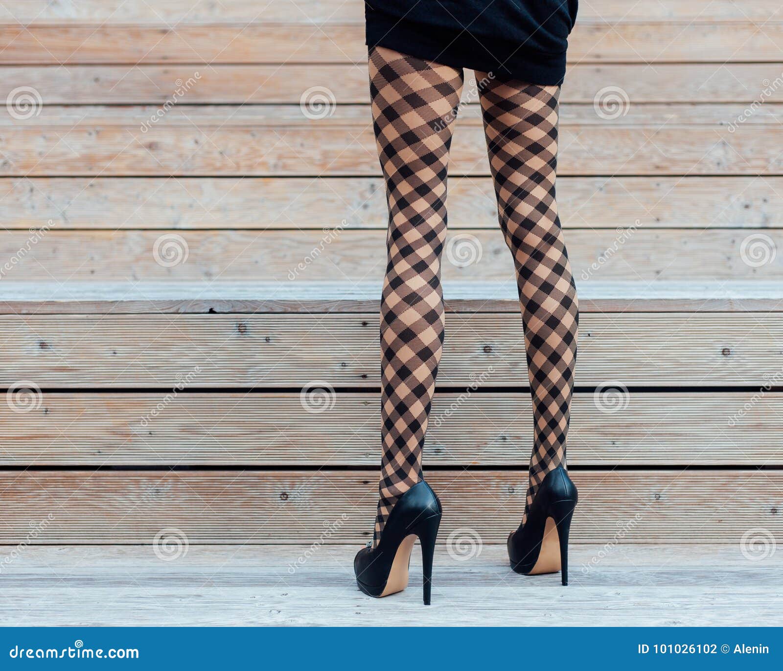 A Girl With Long Legs In Fashionable Fishnet Stockings A Short Black