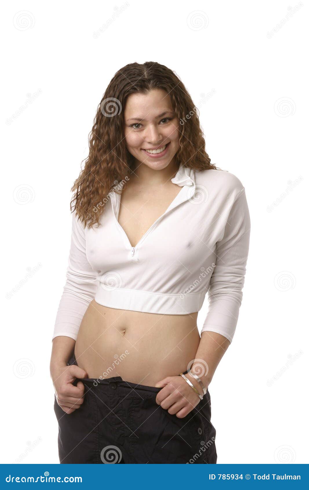 girl posing in short white shirt, showing belly button and wearing silver b...