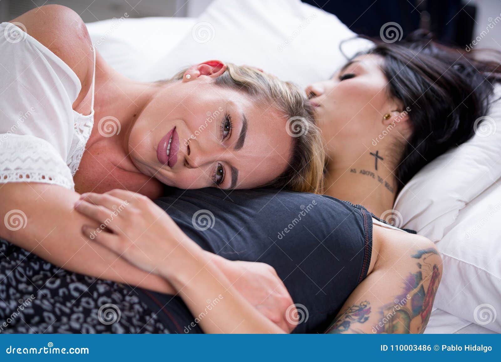 Lesbians Lovers in Bed at Morning, Blonde Girl is Sleeping Over the Brunette Girl Chest, in a White Background Stock Photo