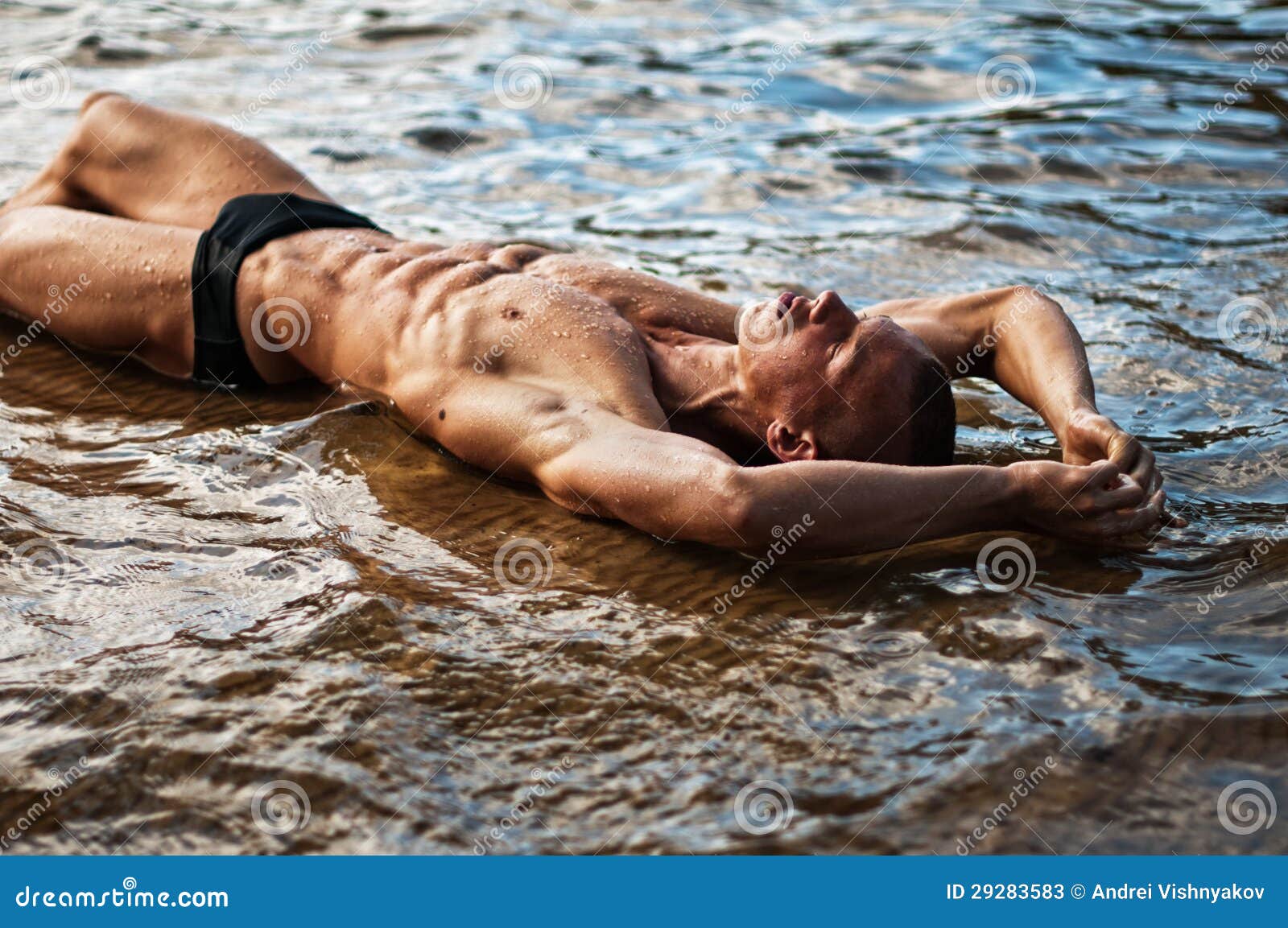 Красивый парень в воде. Мужское тело в воде. Мужчина лежит на пляже.