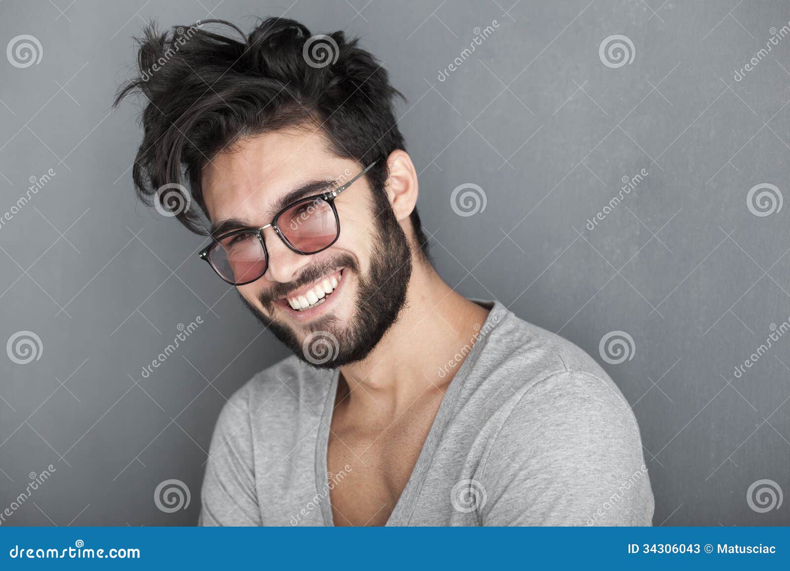 man with beard smiling big against wall