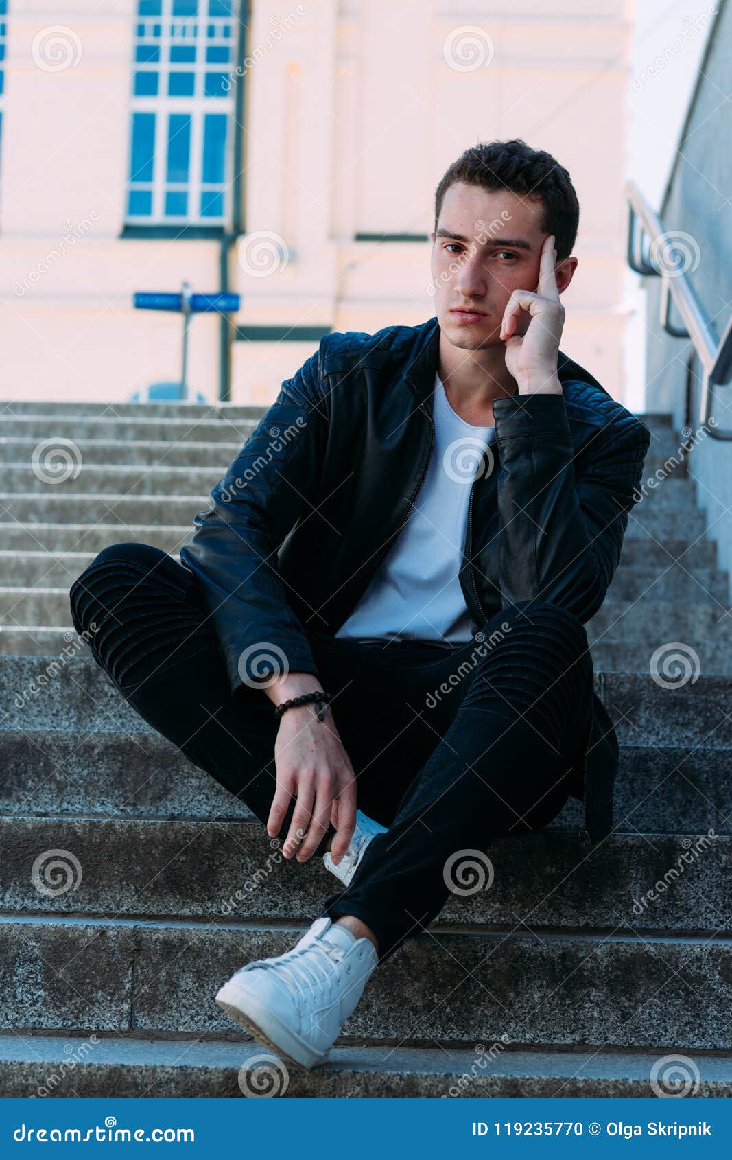 Man Posing Sits on the Steps Near Railing. Handsome Young Man in ...