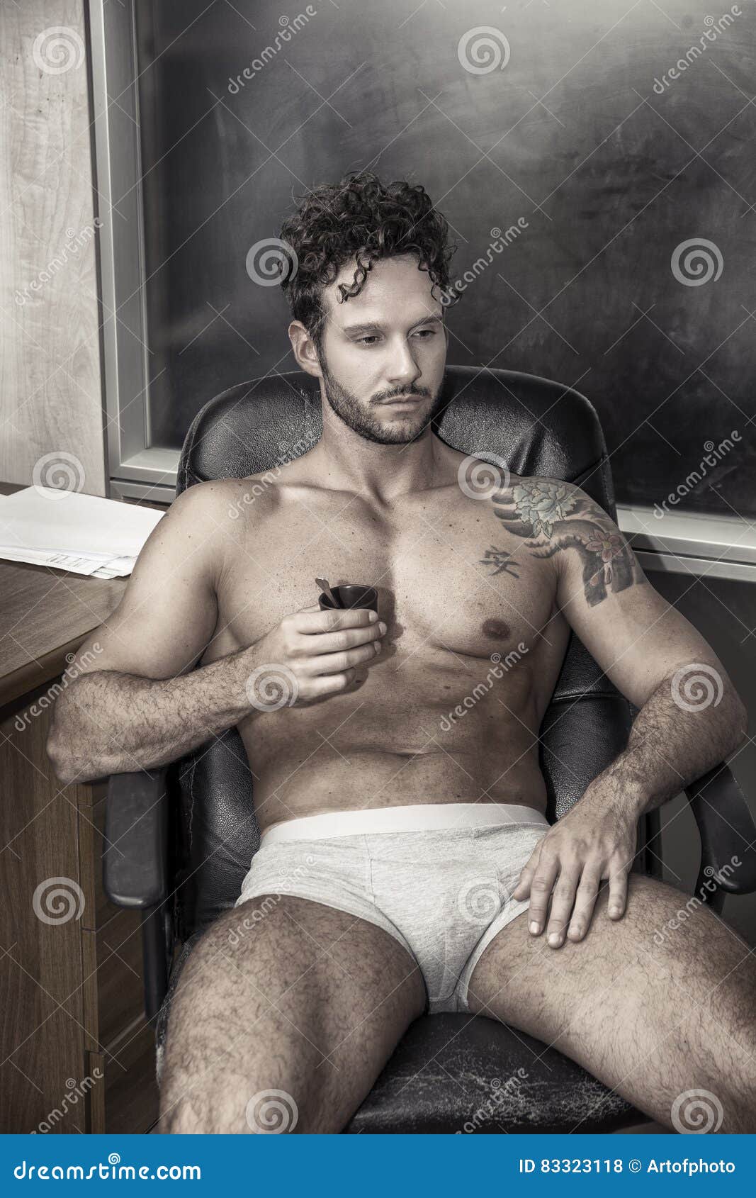 Man Sitting Topless at Office Desk with Coffee Stock Photo pic