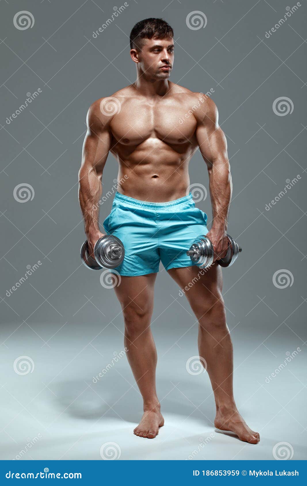 Sexy muscular man working out in gym doing exercises 
