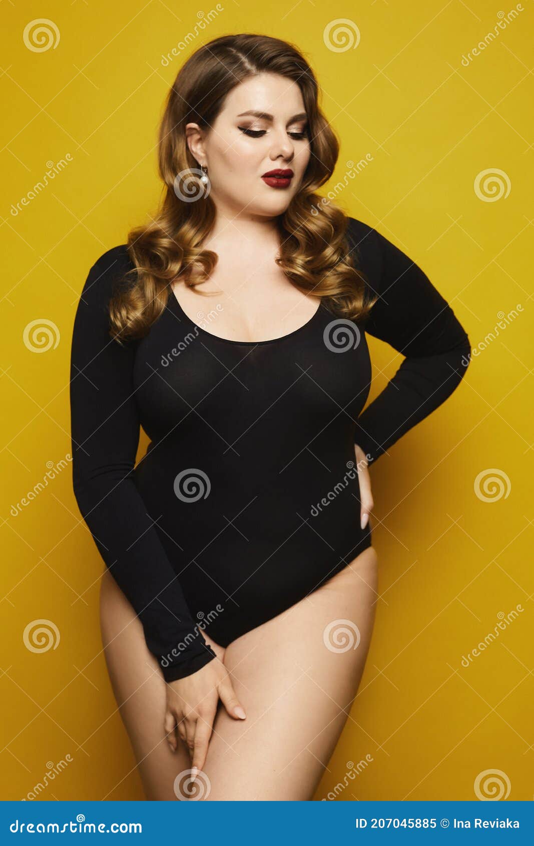 Plump Woman in Black Bodysuit Posing Over Yellow Background. Plus