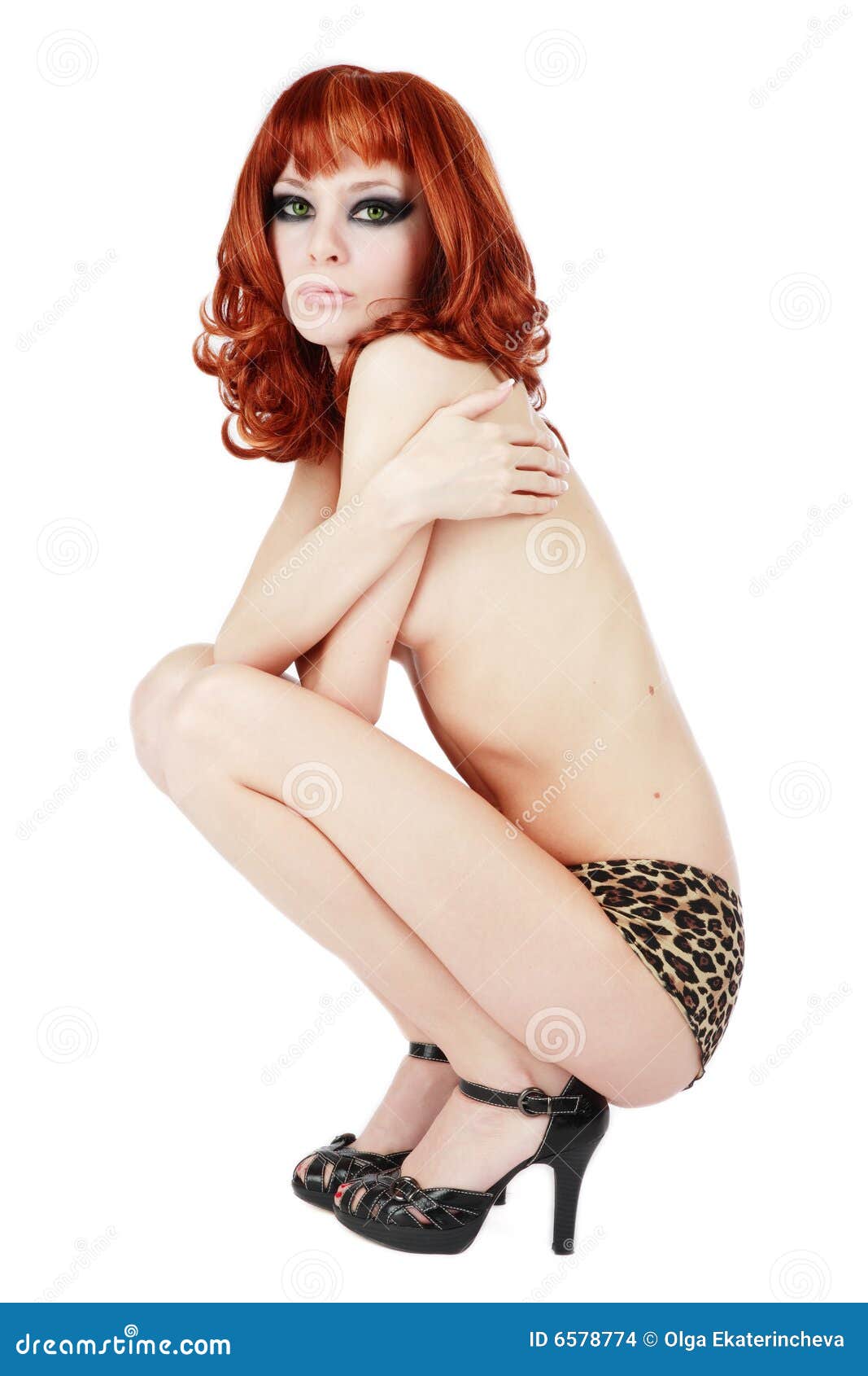 redhead. Beautiful slim red-headed girl in panties with leopard print and black stilettos sitting on white background