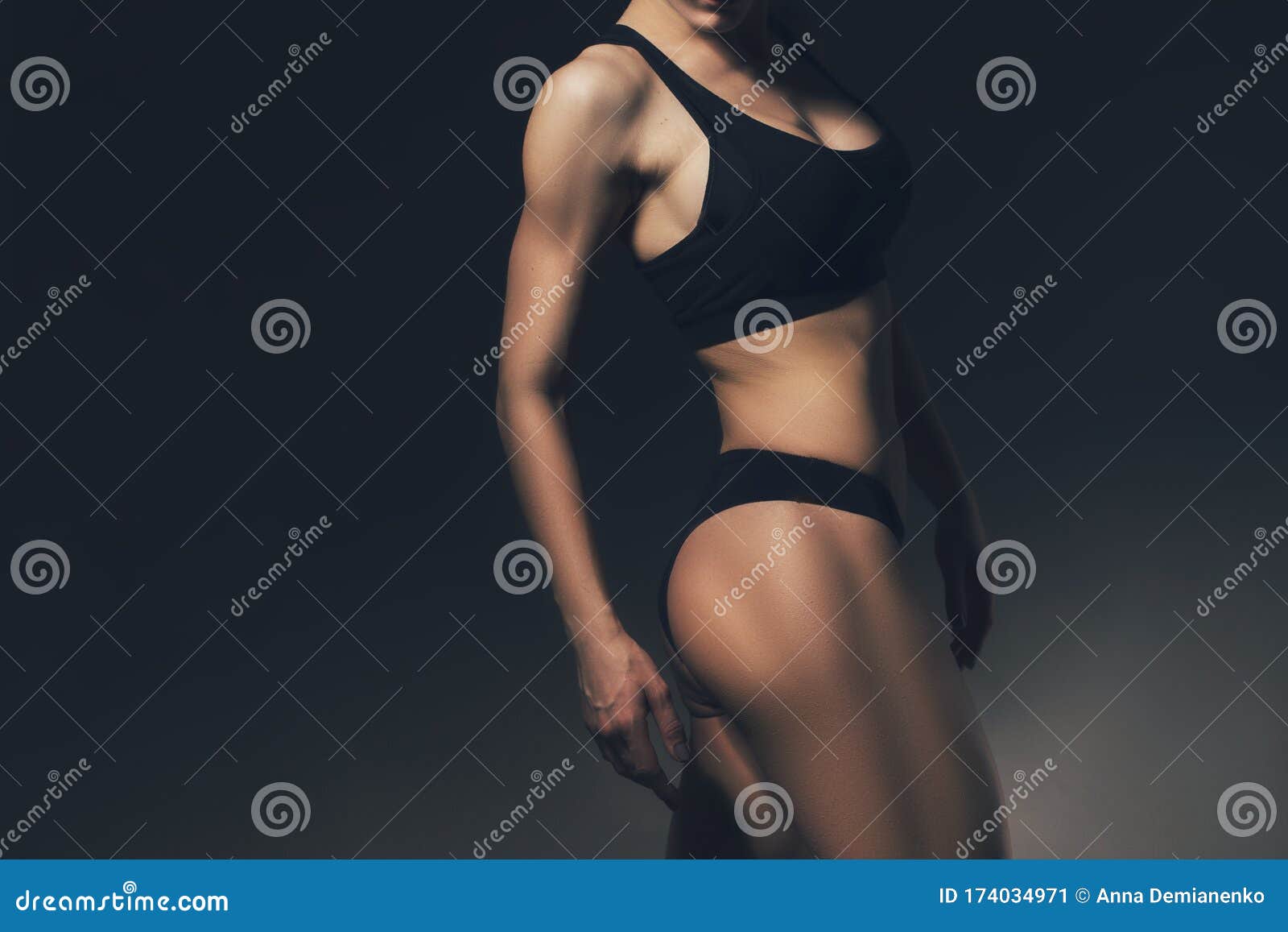 sexy slim fit woman body. muscled back. sportswear. dark background