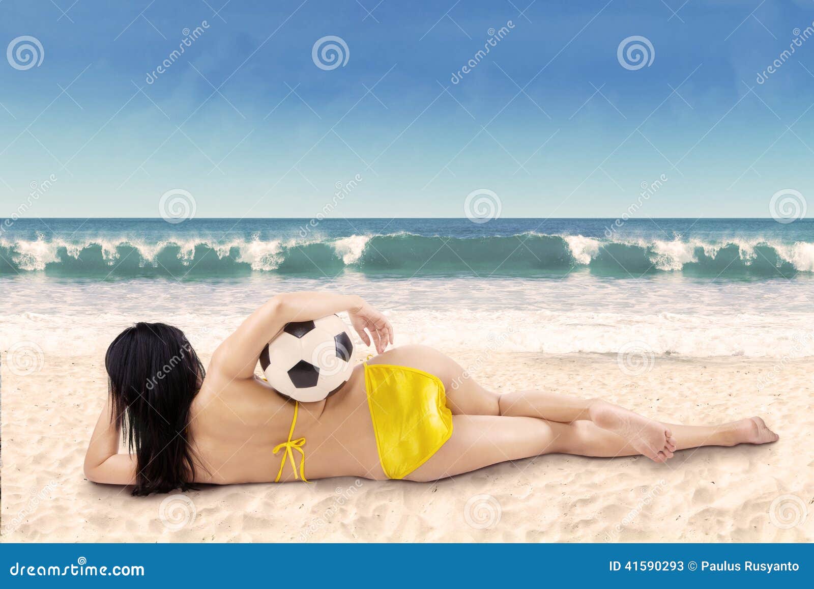 Sexy vrouw met bikini die op strand liggen. Achtereind sexy vrouw met een voetbalbal die op het strand liggen