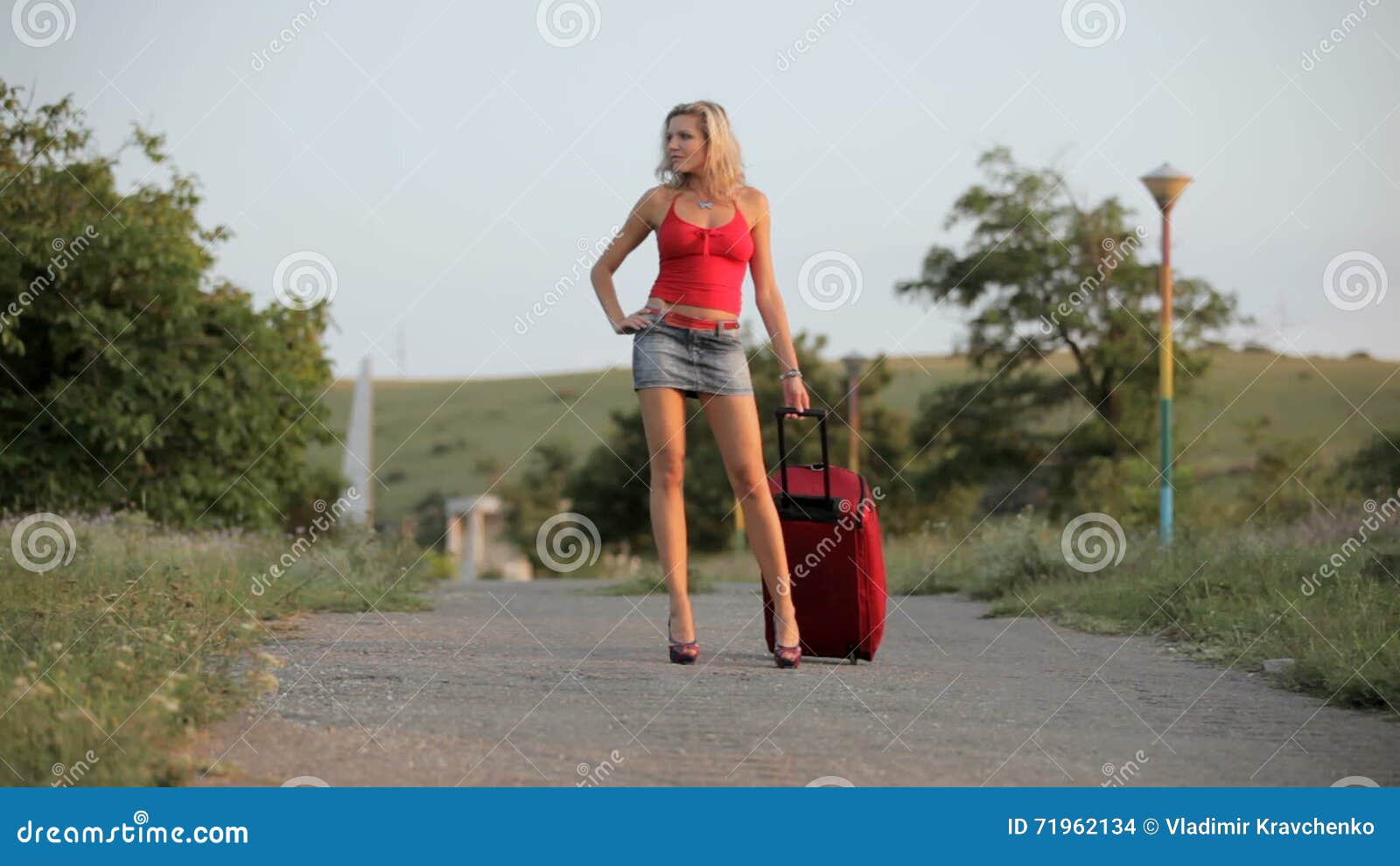 Leggy temptress in short skirt walking on the sidewalk
