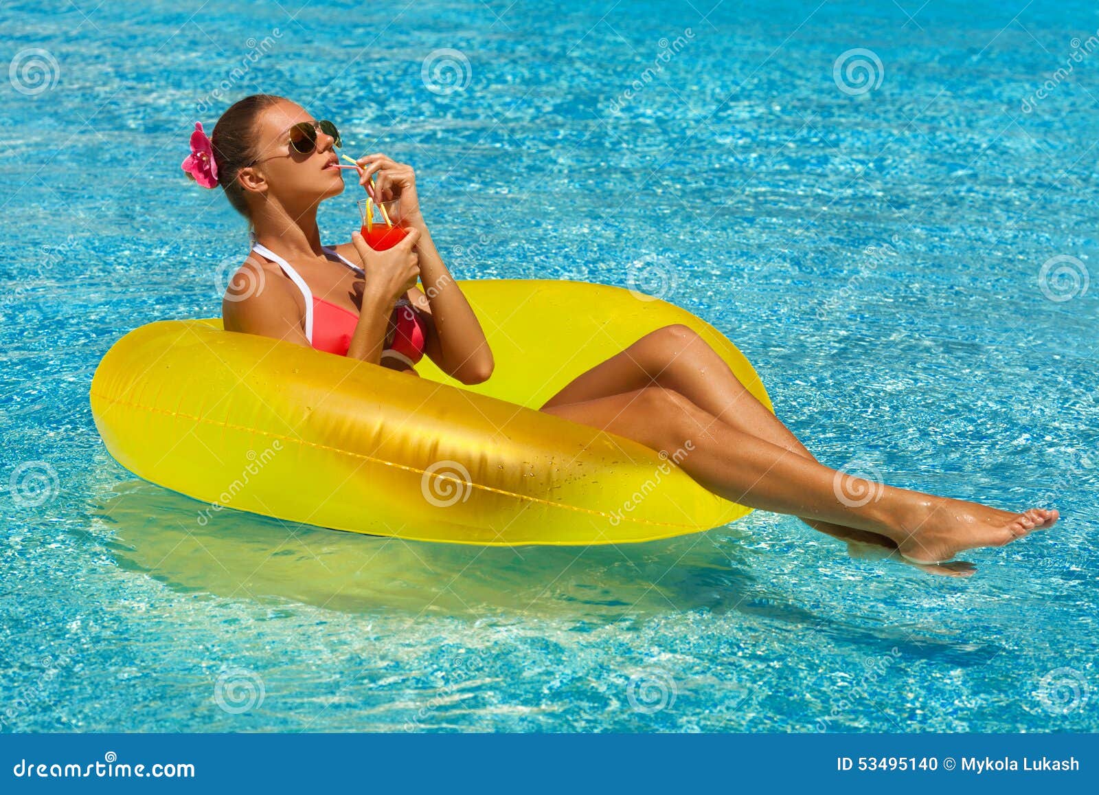 woman in bikini enjoying summer sun and tanning during holidays in pool with a cocktail