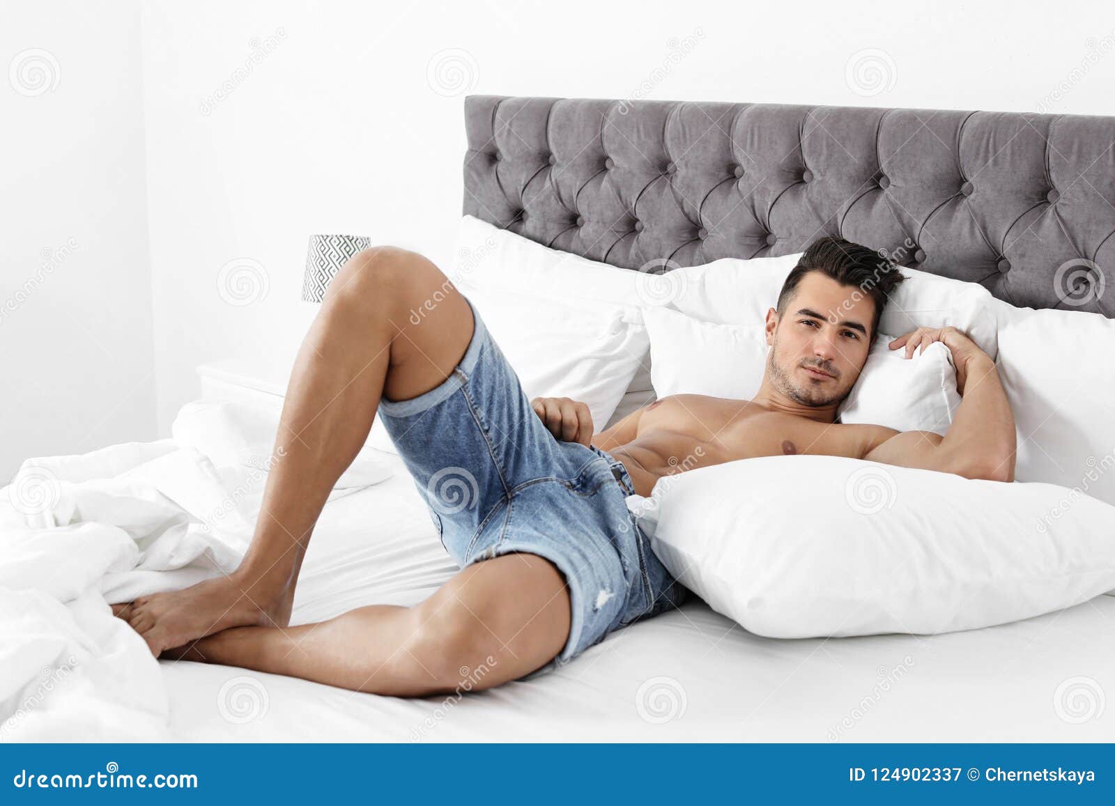 Young Man Lying On Bed With Soft Pillows Stock Image - Image of male, athle...