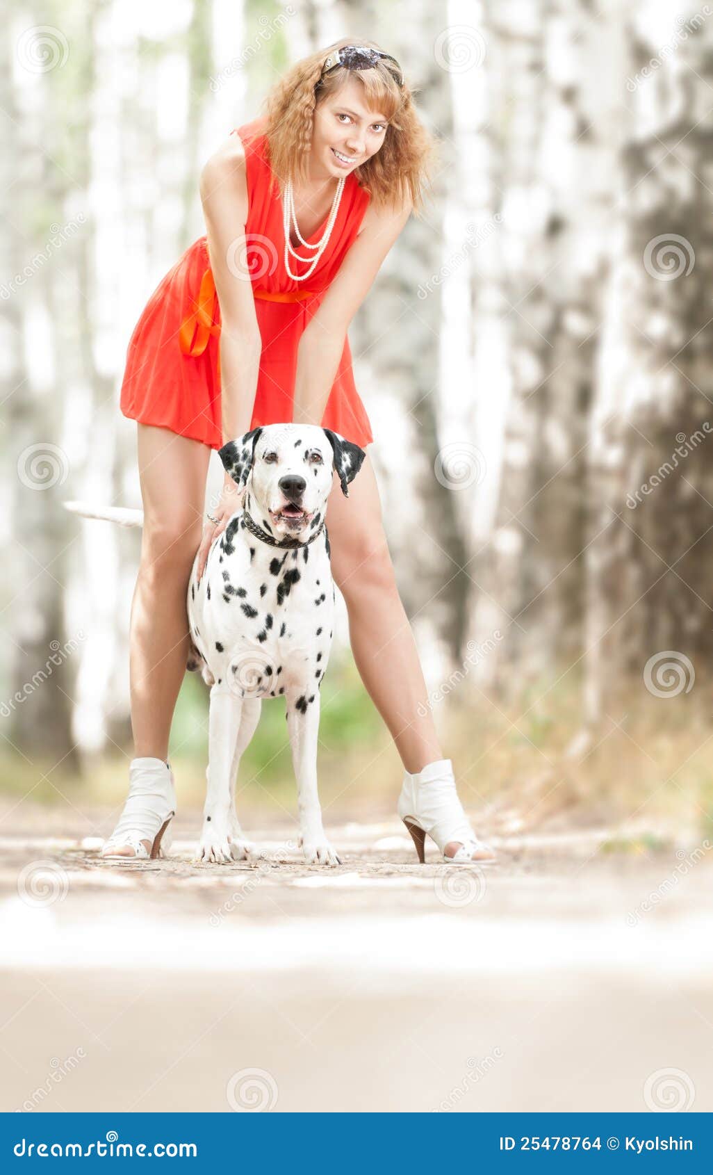 young woman with dog. Beautiful and young woman in red dress with dalmatian dog in summer forest.