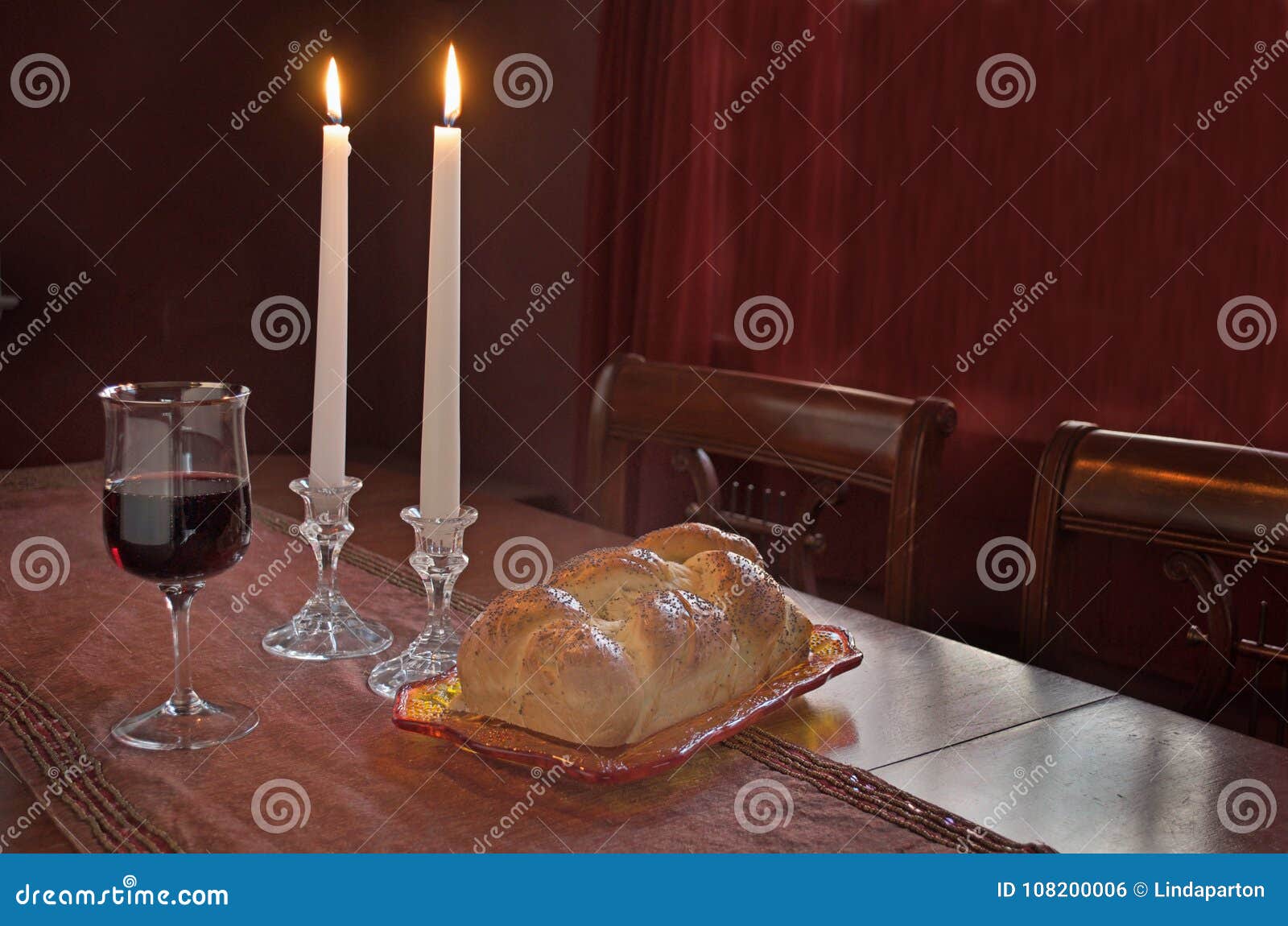 shabbat observance at sunset: challah, glass of wine, two lit candles