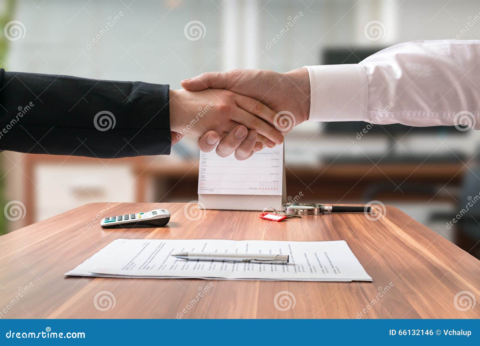 shakehand of lawyer and business woman sitting behind desk with agreement