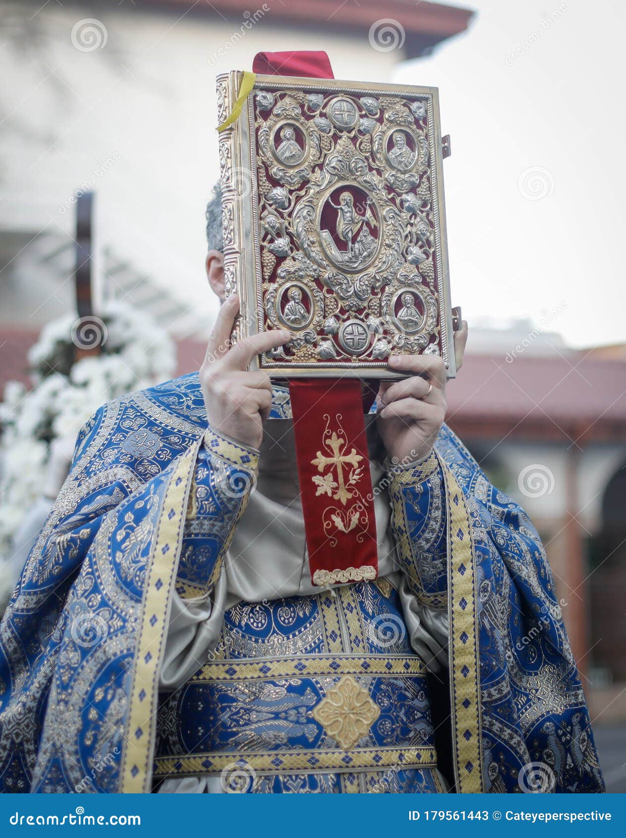 shallow depth of field selective focus details with a romanian orthodox christian priest holding a holy bible outside a church