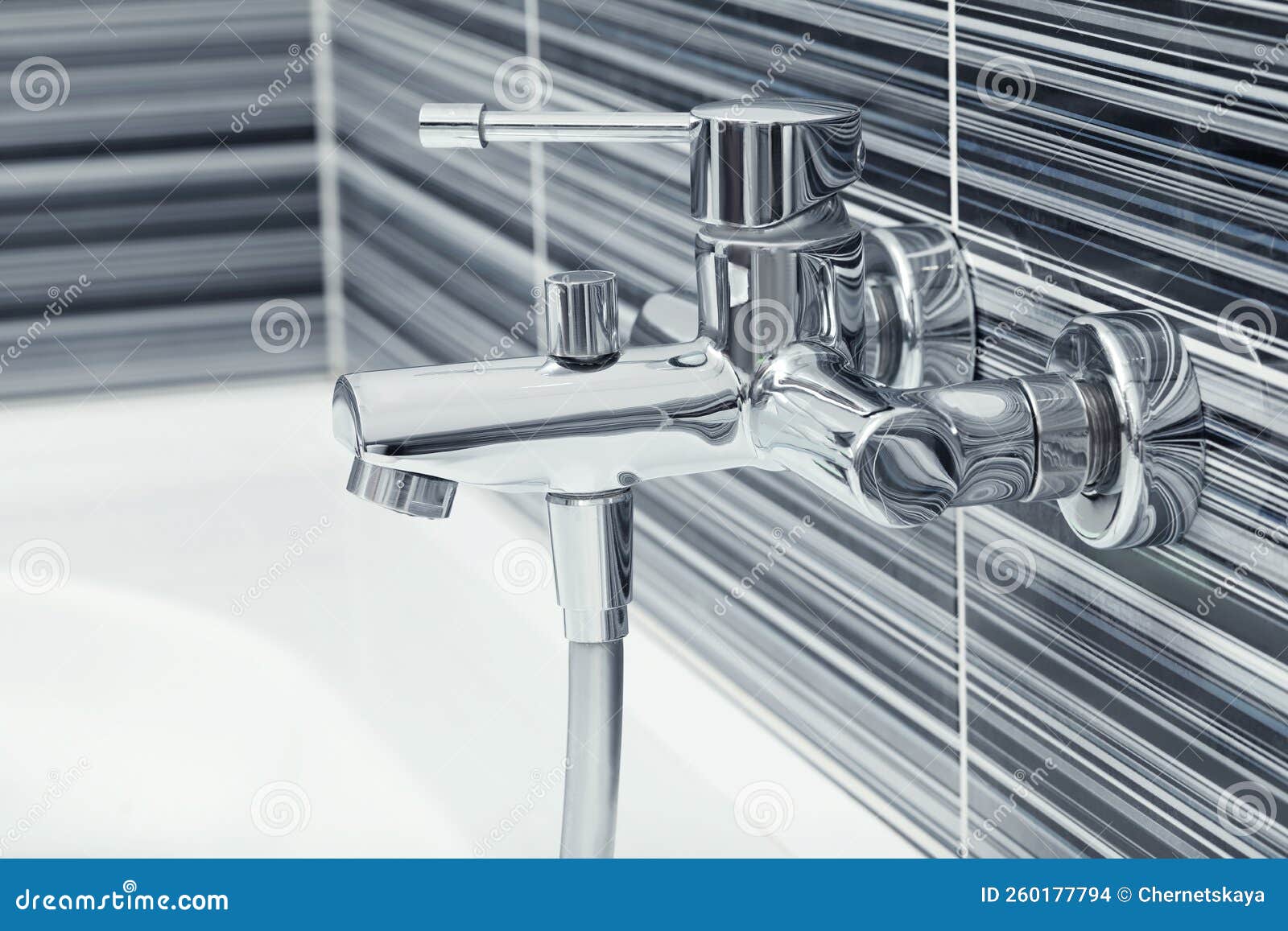 Shiny Bath Water Tap Installed on Black and White Wall Stock Photo