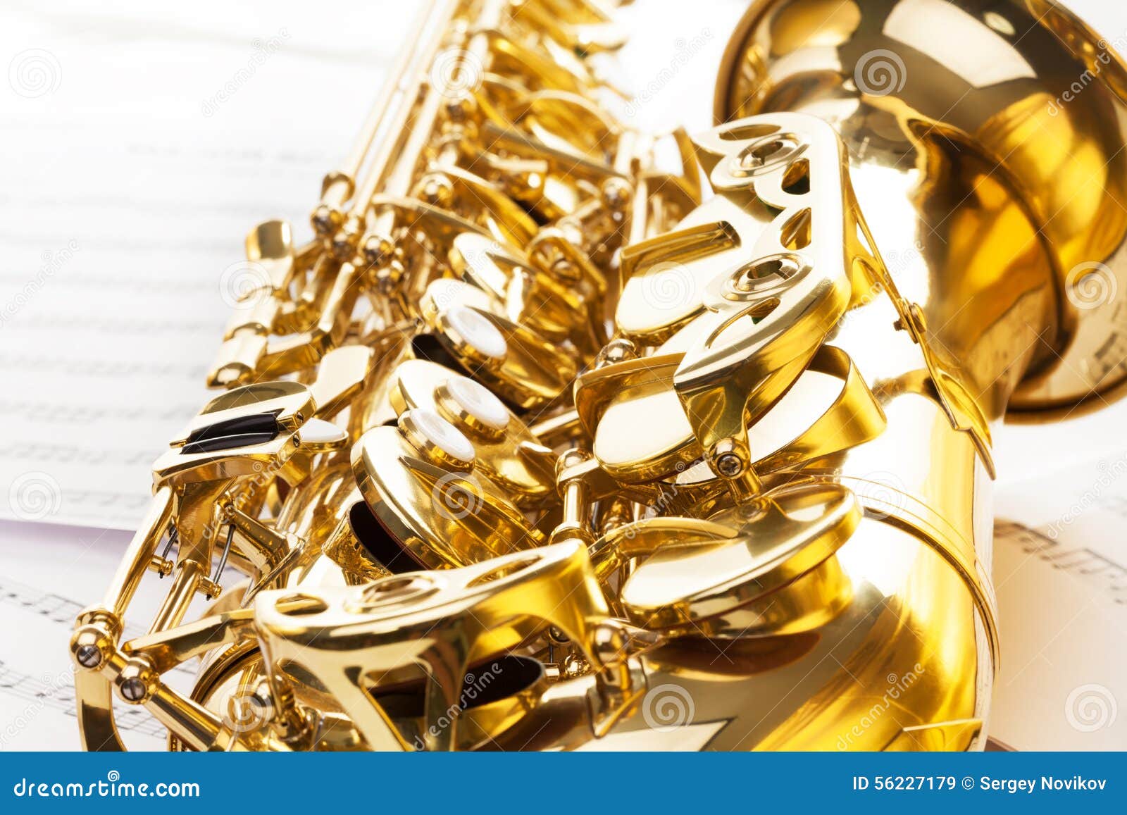 Shiny golden bell and keys of alto saxophone on the musical notes background with standard scales exercises