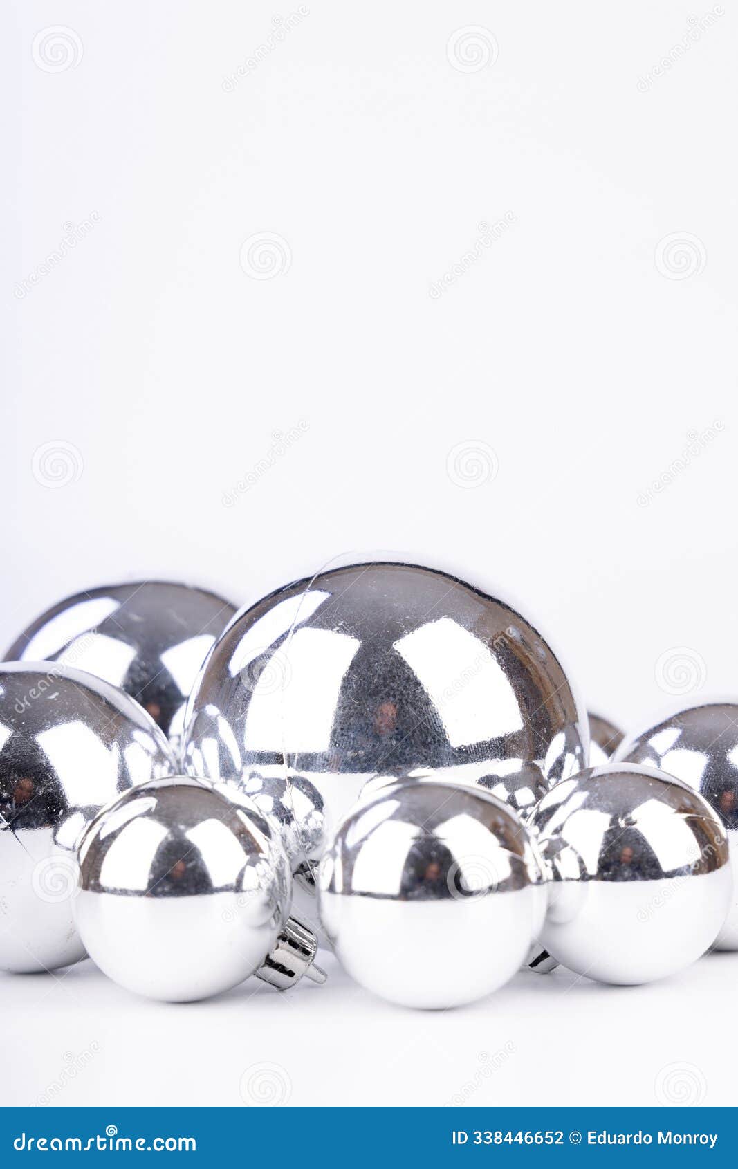 shiny silver christmas balls of various sizes used as decorations on a white background, arranged in an elegant festive setting