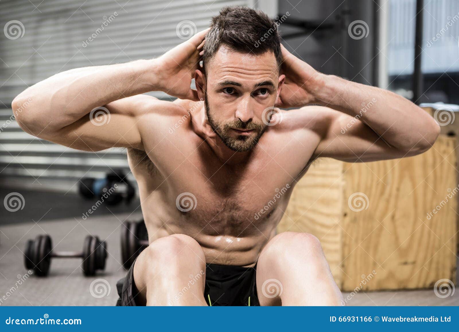 Muscular shirtless man workout with kettlebells in L Sit position outdoors.  Stock Photo