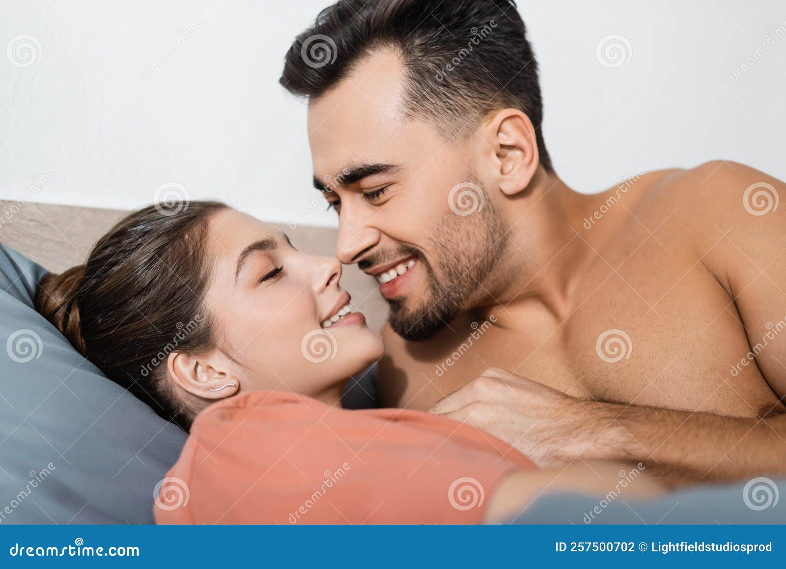 Muscular Man Hugging Seductive Woman In Bra Lying On Bed Stock