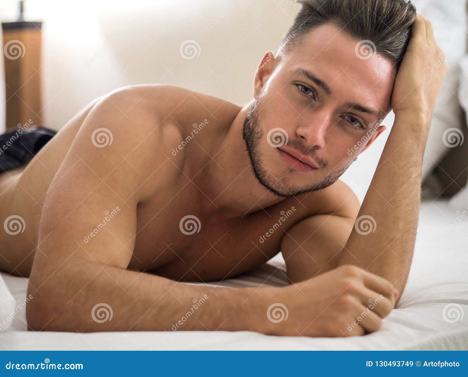 shirtless male model lying alone on his bed