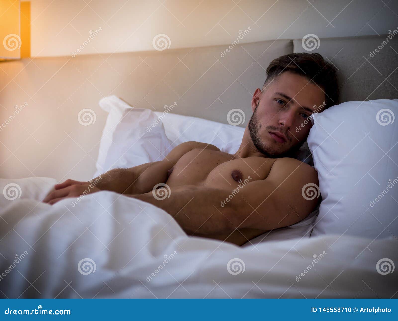 shirtless sexy male model lying alone on his bed