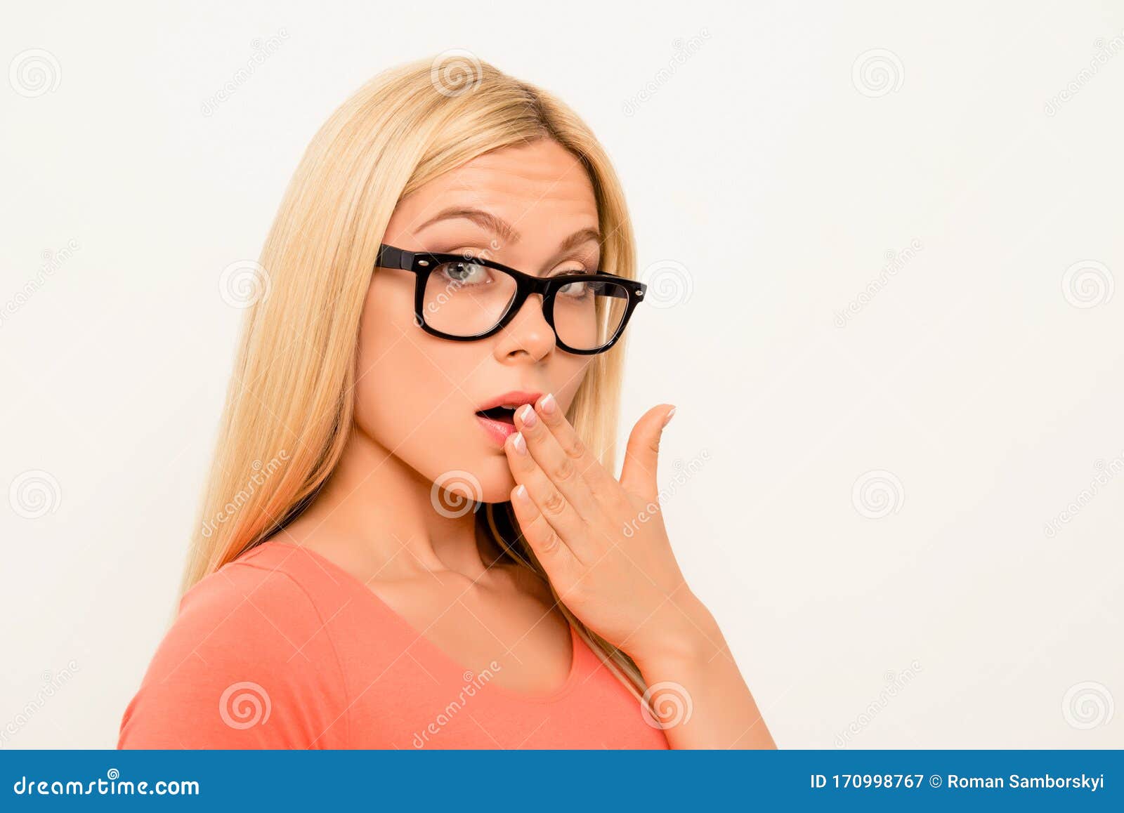 shocked brainy girl in glasses holding hand near mouth