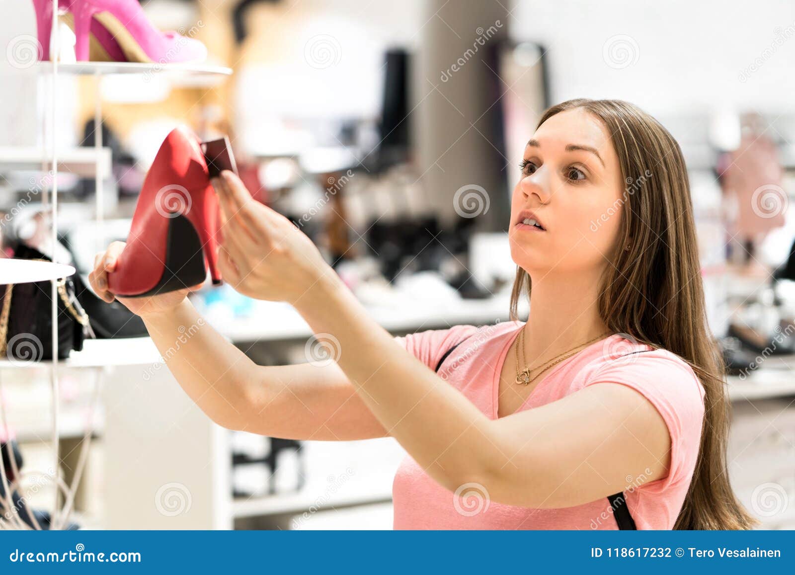 shocked woman looking at price tag of too expensive shoes.