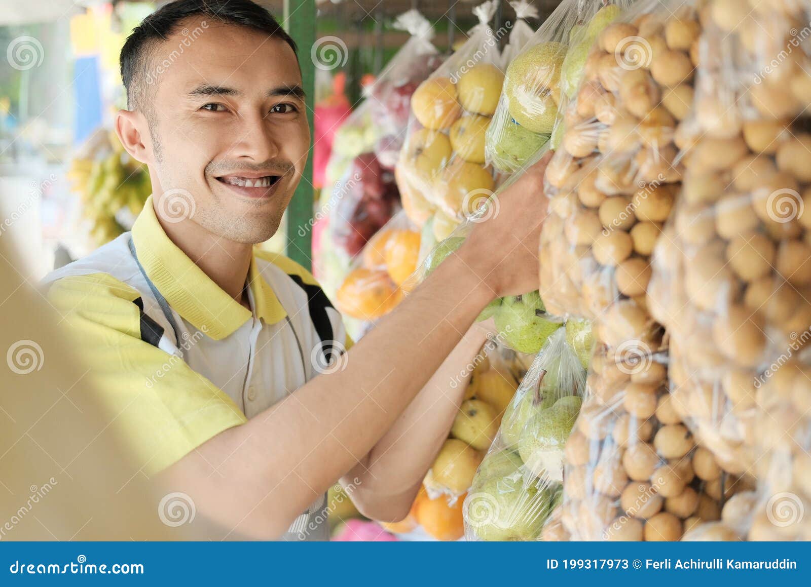 Shop Assistant Arranging Hanging Plastic Fruit Packaging Stock Image