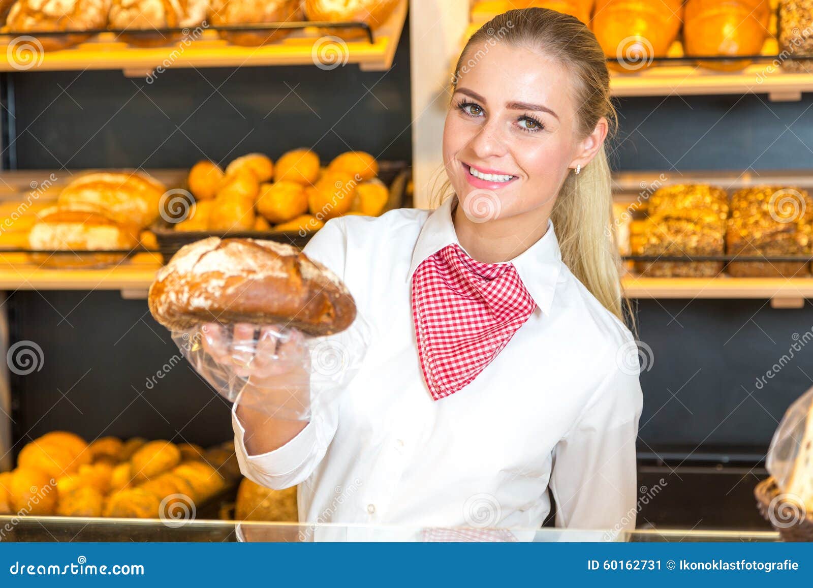 Shopkeeper in Bakery Presenting Loaf of Bread To Client Stock Image