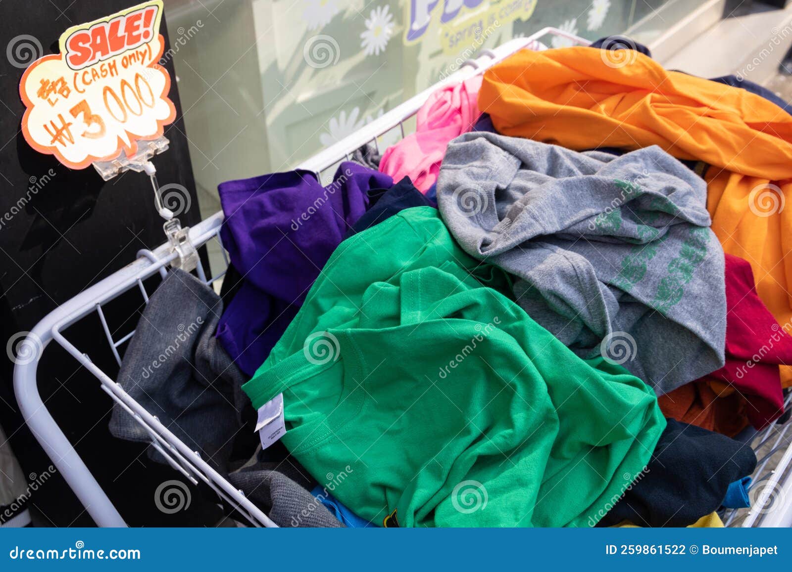 a shopping basket filled with clothes with a note: sale, cash only.