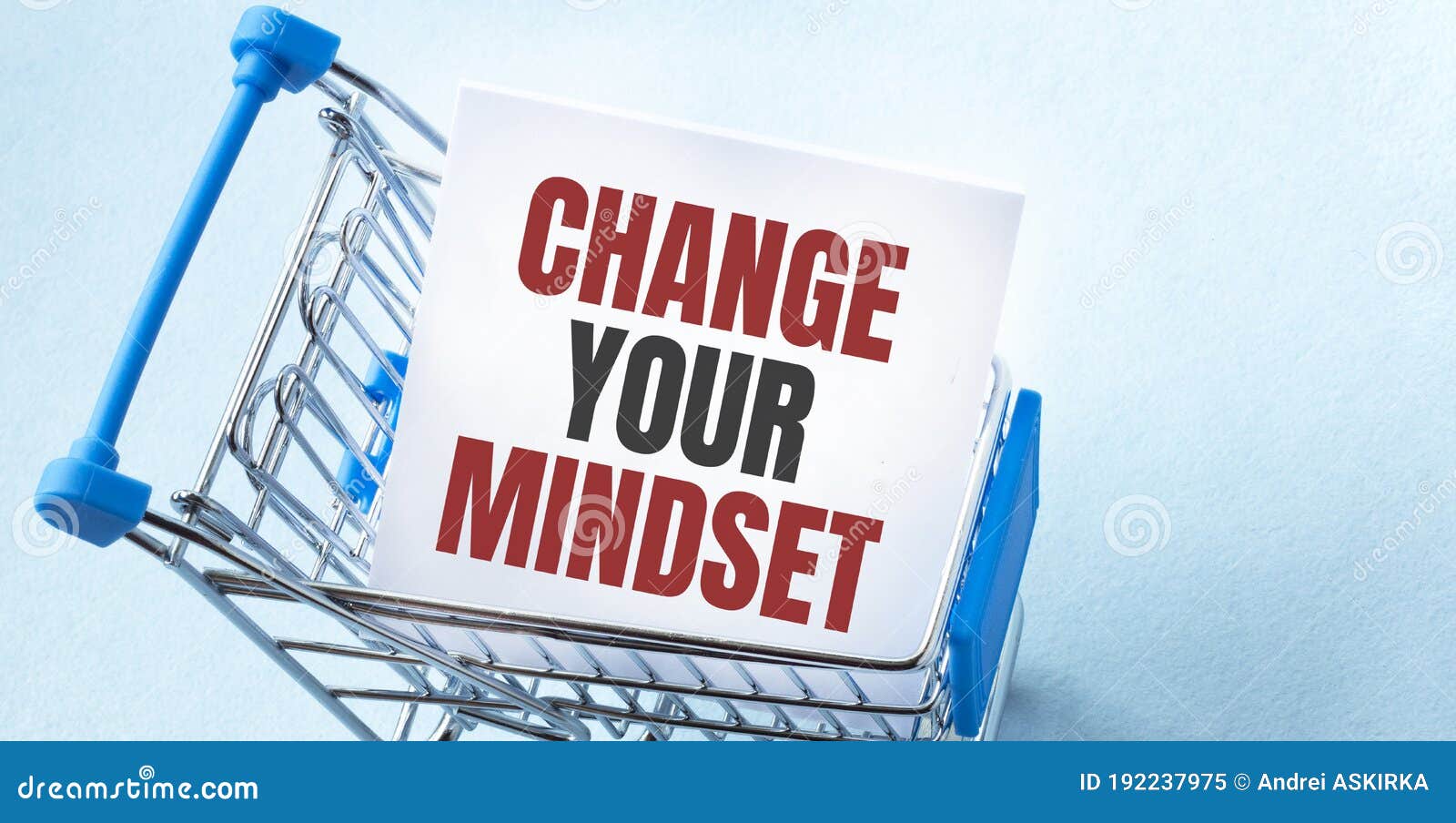 shopping cart and text change your mindset on white paper note list. shopping list concept on blue background