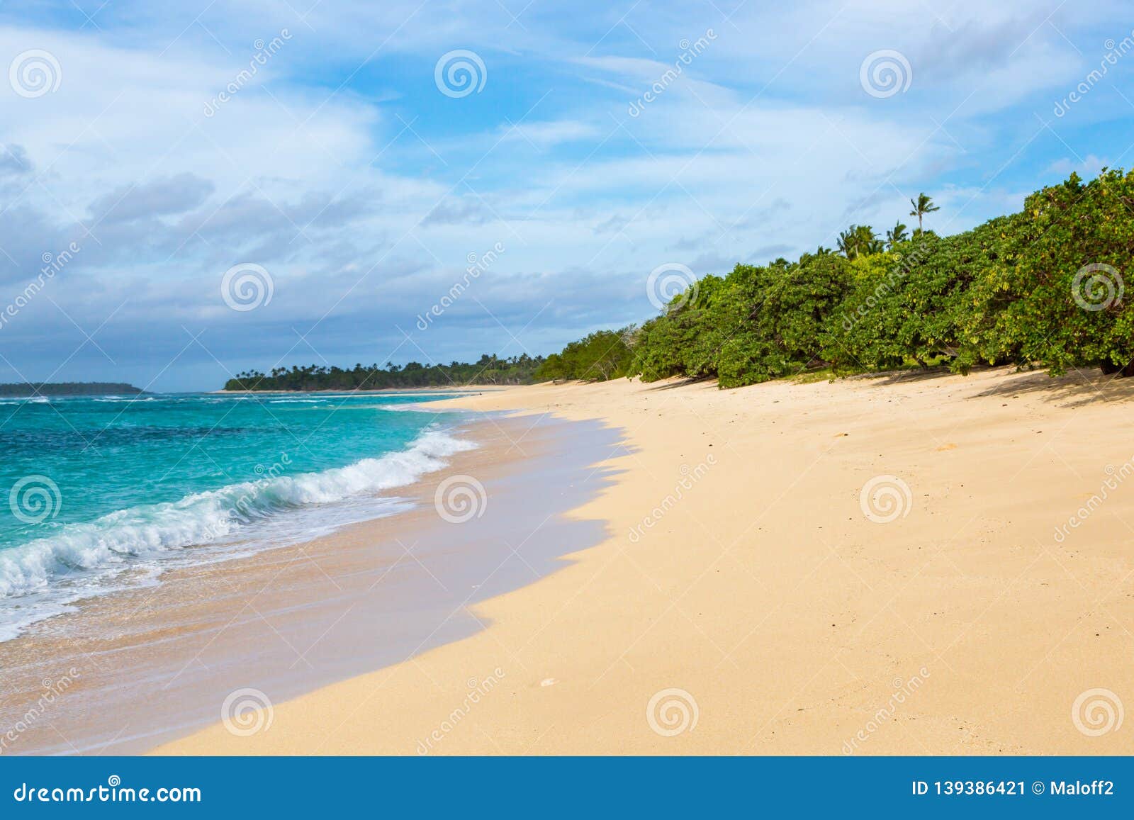 shore of an azure, turquoise, blue lagoon. waves, surf, swash at a remote empty idyllic sandy beach on foa island, haapai, tonga.