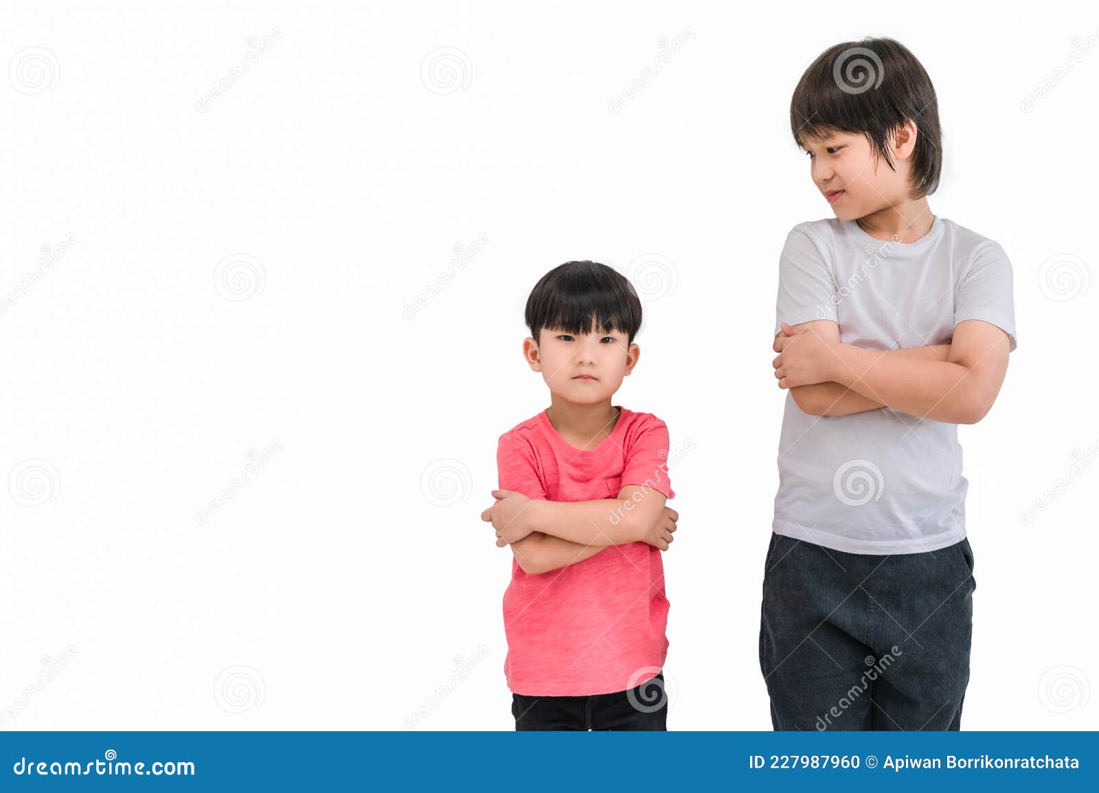 short child boy in red t shirt and tall child boy in white t shirt standing arms crossed and looking face  on white