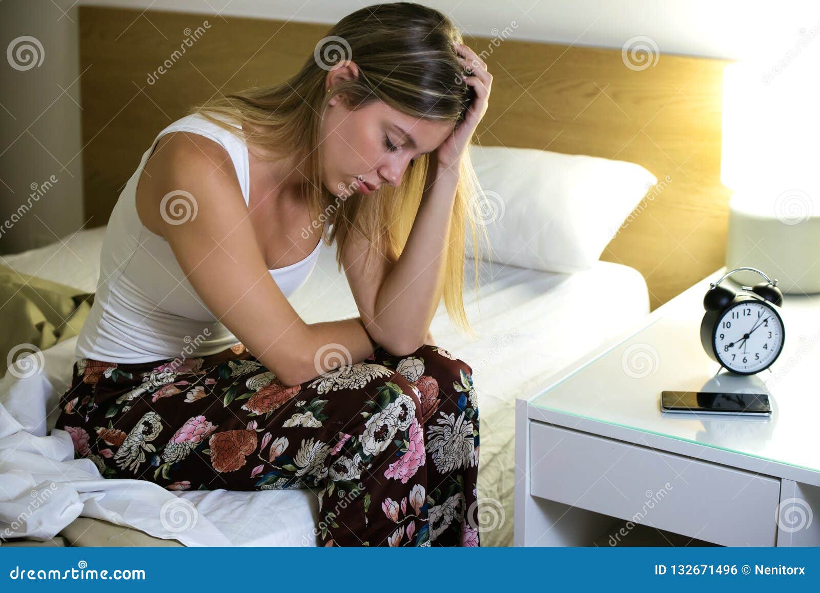 beautiful young exhausted woman suffering insomnia sitting on bed in the bedroom at home.