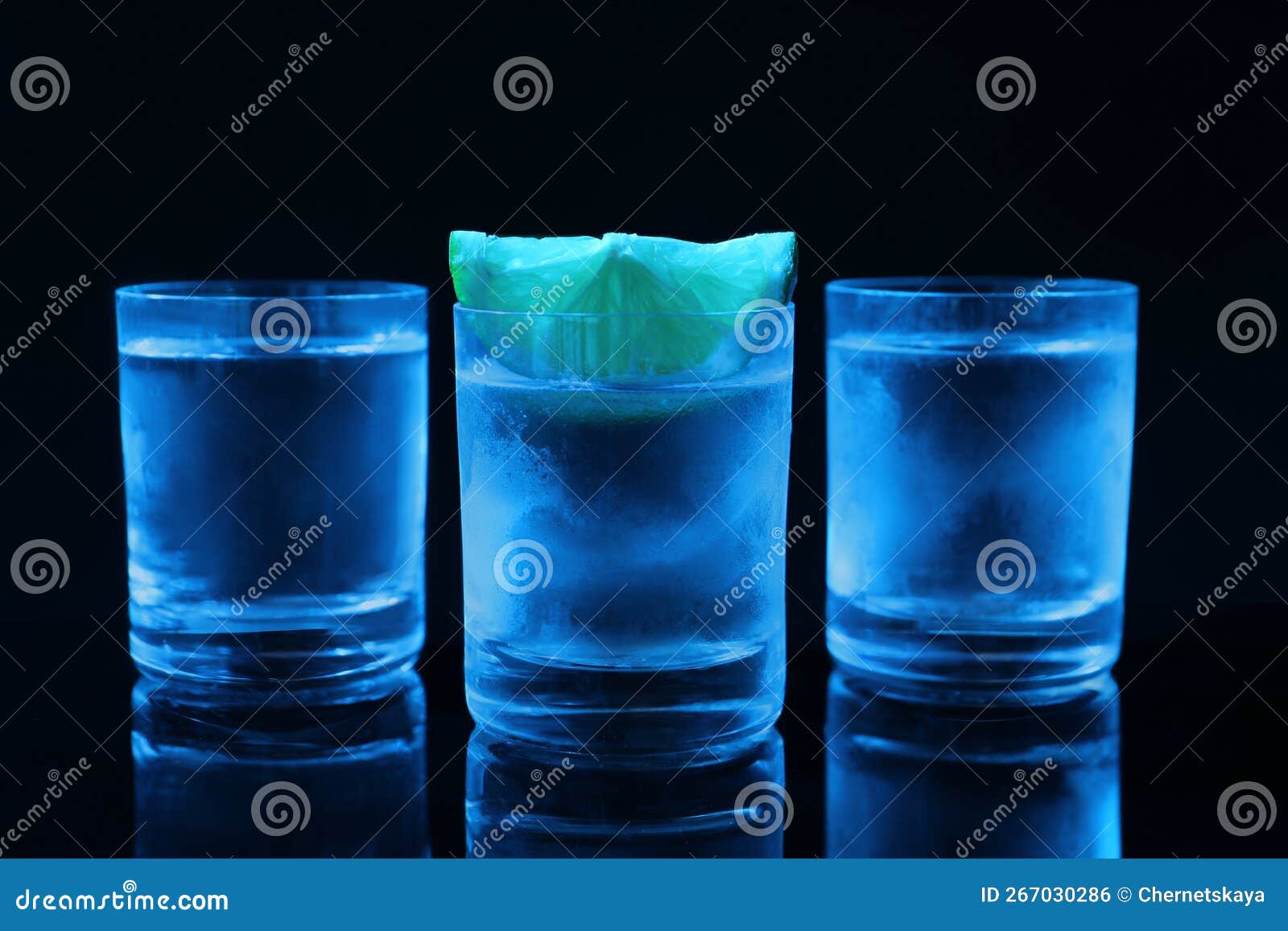 Shot Glasses of Vodka with Lime Slice on Dark Background Stock Photo
