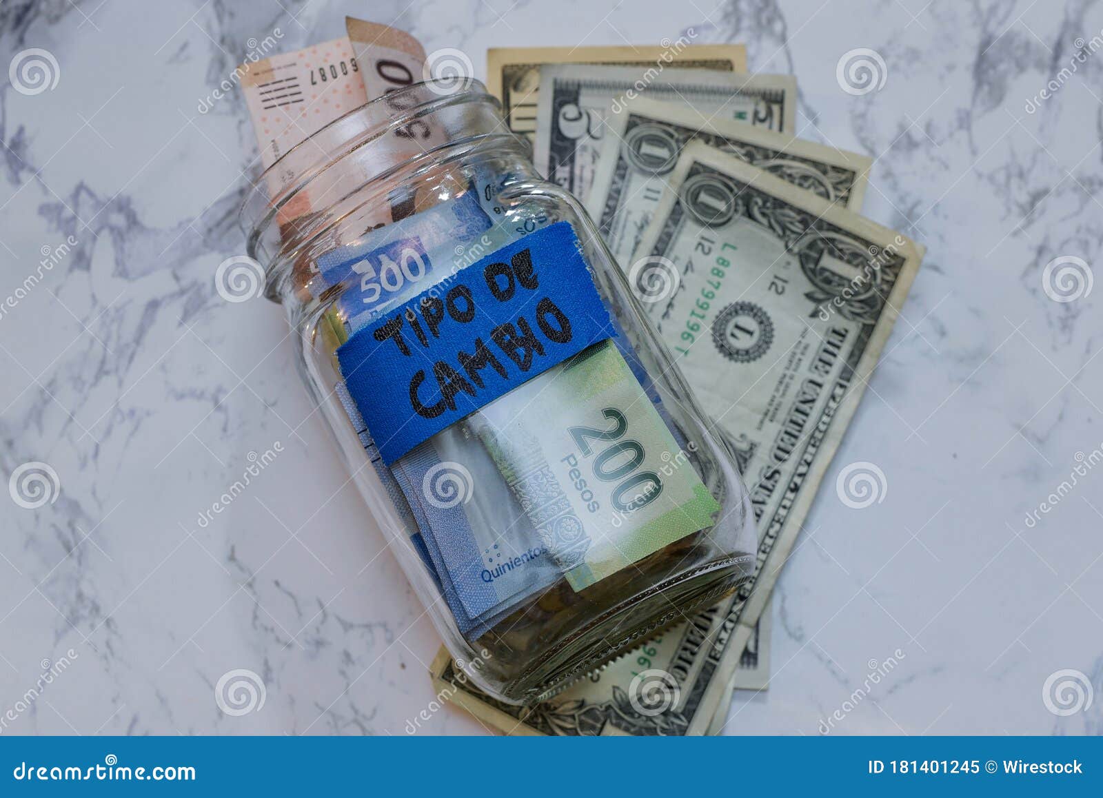 shot of pesos and dollars in a jar with a [tipo de cambio - exchange rate] sign on it on the table