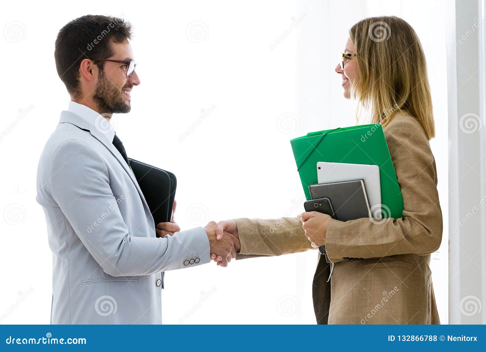 two attractive bussines partners shaking their hands in the office.