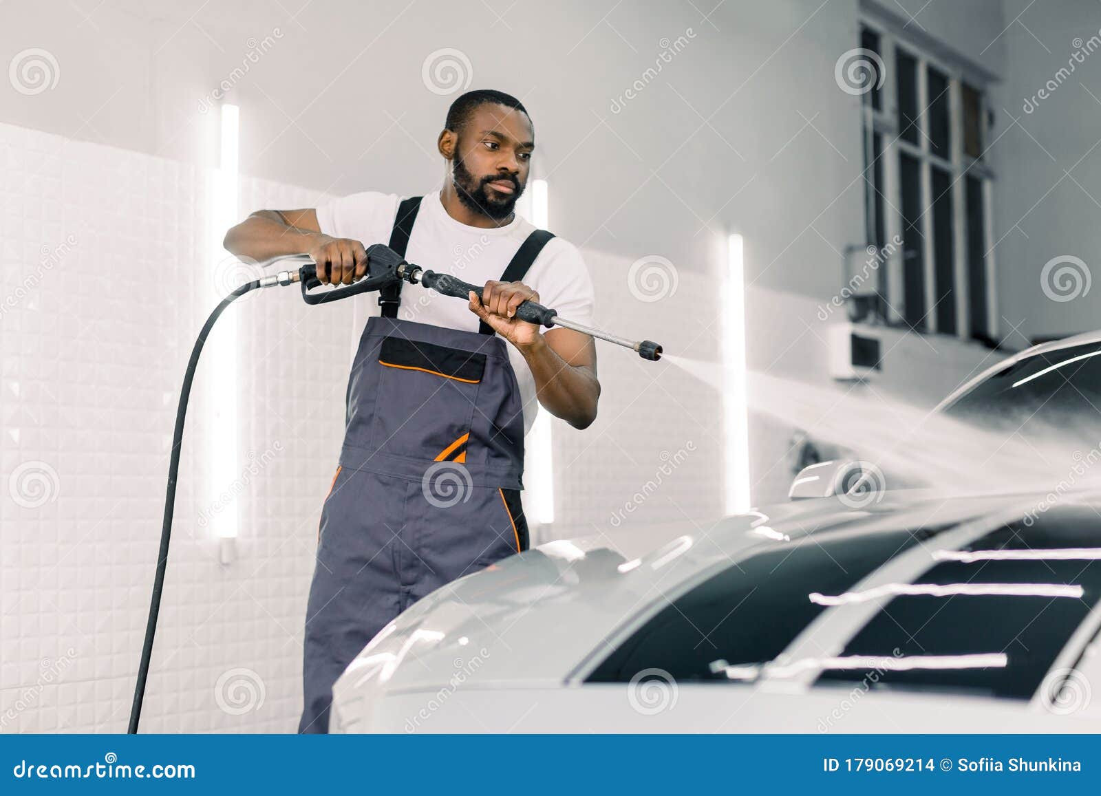 Person washing car with water and soap in carwash. Man with high